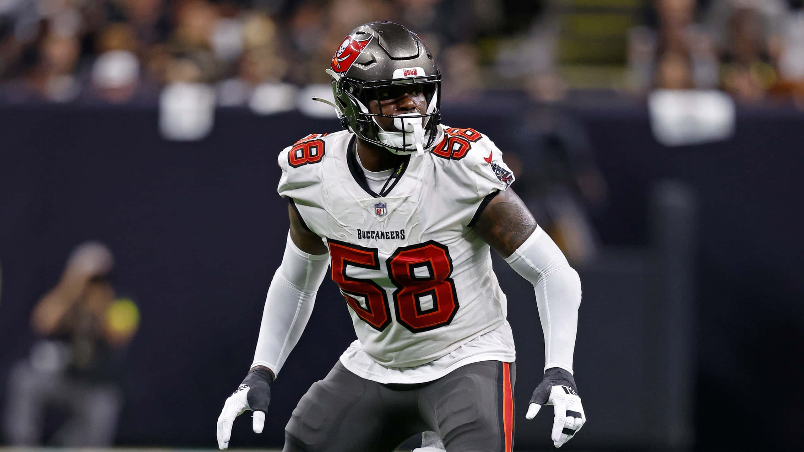 NFL球員沙奎爾·巴雷特外線後衛 壁紙 — 一名坦帕灣海盜隊美式足球員身穿白色58號球衣，在球場燈光下的夜間比賽中全力奔跑。