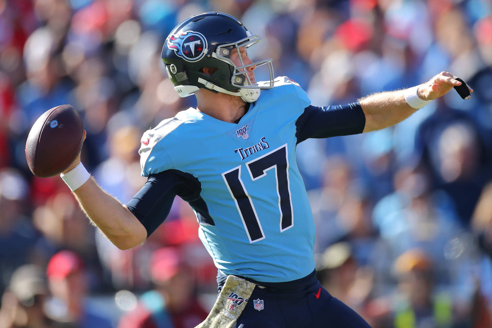 NFL瑞安·坦尼爾投出達陣傳球 壁紙 — 一位身穿淺藍色球衣17號的田納西泰坦四分衛在日間比賽中擲出橄欖球，背景是模糊的體育場人群。