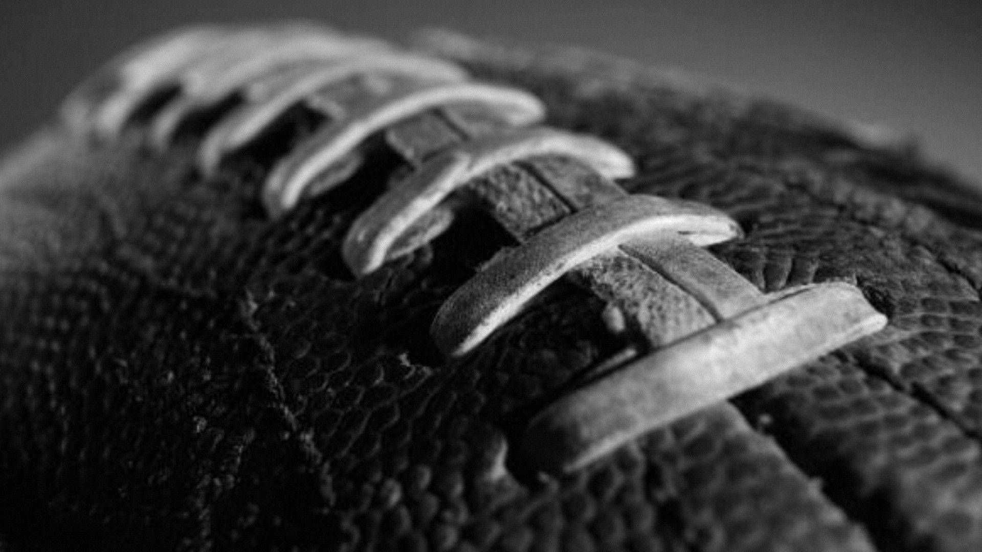 NFL美式足球特寫 壁紙 — 美式足球的紋理皮革和鞋帶的特寫黑白照片，顯示磨損和污垢。