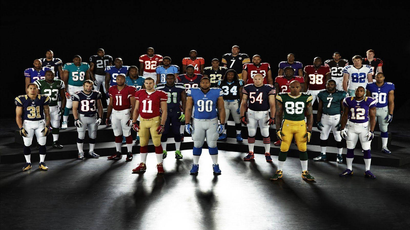 NFL美式足球運動員群像 壁紙 — 一群身穿球隊制服的美式足球NFL球員在黑暗的舞台上，在戲劇性的聚光燈下排成隊形。