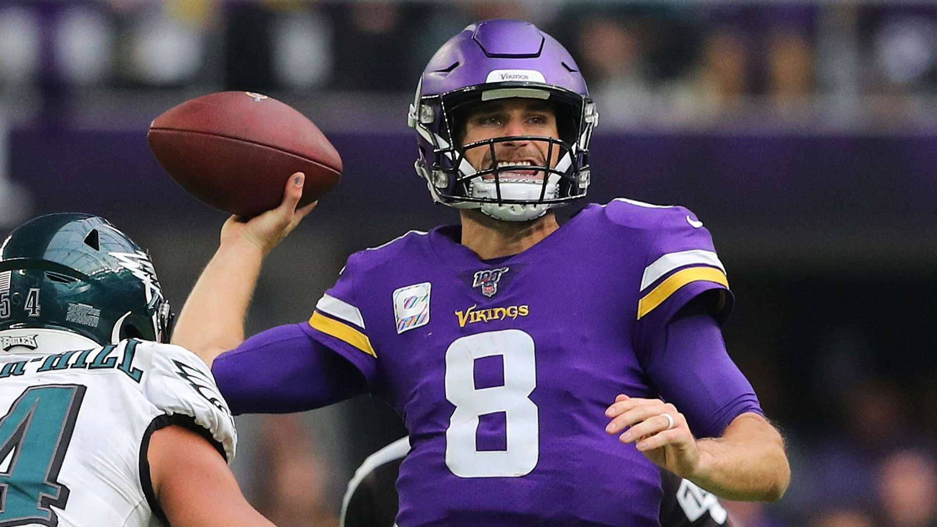 NFL職業足球明星柯克·庫西恩斯 壁紙 — 明尼蘇達維京人隊的四分衛身穿紫色8號球衣，在夜間比賽中準備投擲美式足球。