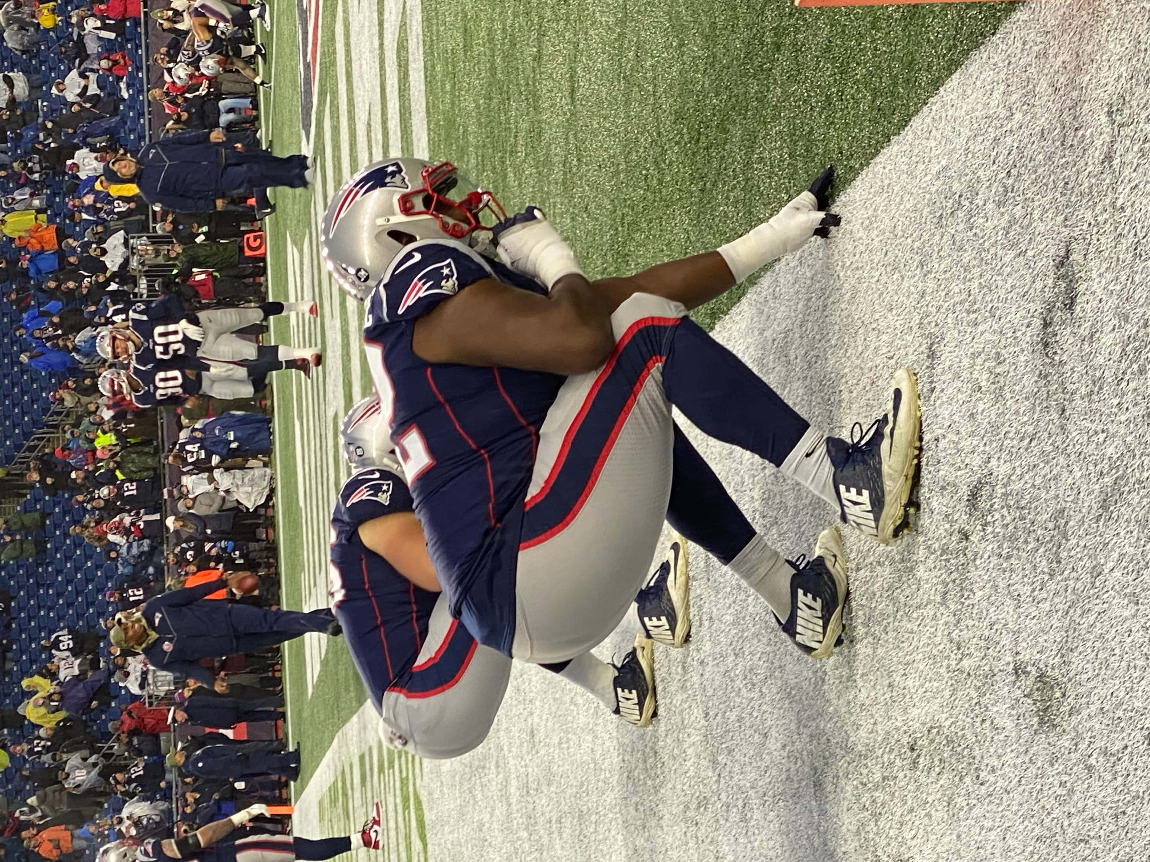 NFL賽事的巔峰精彩 壁紙 — 兩名身穿新英格蘭愛國者隊球衣的足球運動員在雪地球場上慶祝達陣，看台上坐滿了球迷。
