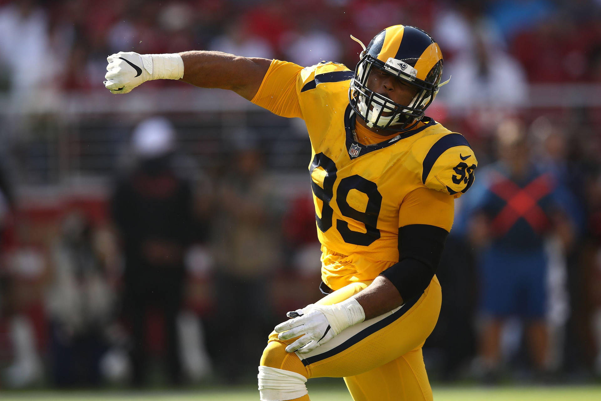 NFL運動員阿隆·唐納德黃色球衣 壁紙 — 一名身穿黃色球衣、號碼39的足球運動員在陽光普照的球場上動態慶祝，背景是模糊的體育場觀眾。