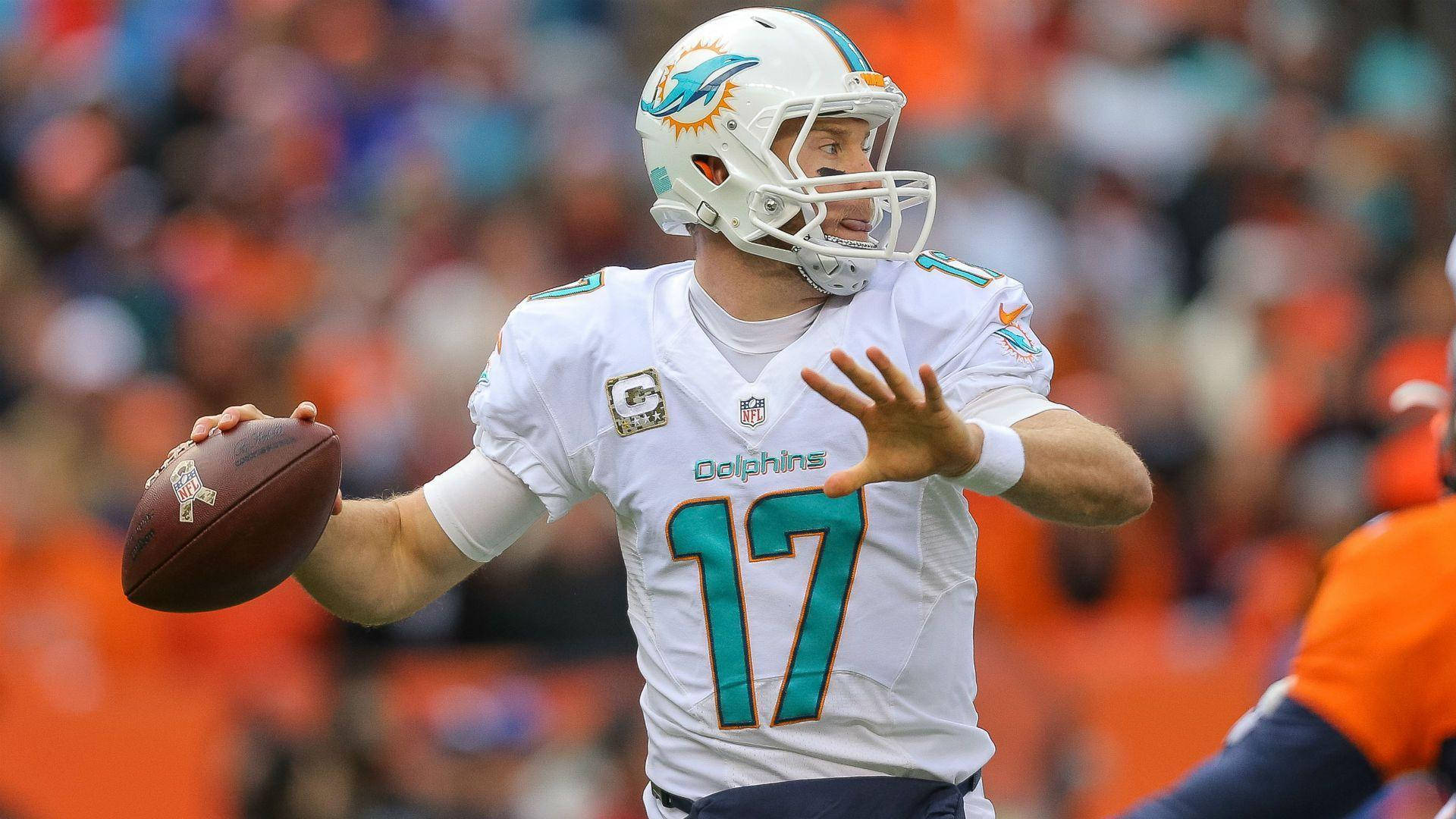 NFL邁阿密海豚隊四分衛瑞安·坦尼爾 壁紙 — 邁阿密海豚隊四分衛身穿白色17號球衣，在白天比賽中準備投擲橄欖球，背景是模糊的橙色人群。