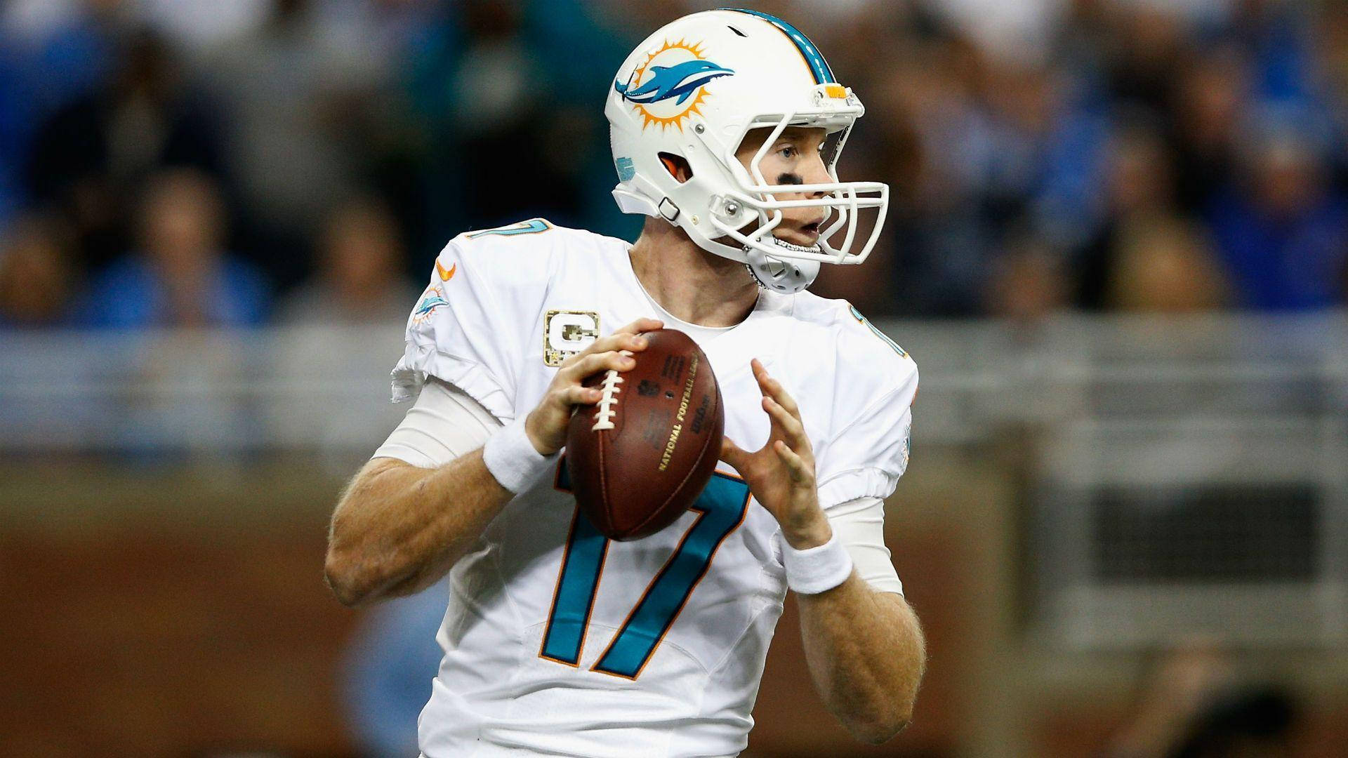 NFL邁阿密海豚隊瑞安·坦尼爾手持足球 壁紙 — 一名身穿白色球衣的邁阿密海豚四分衛在體育場燈光下準備在比賽中擲出橄欖球。