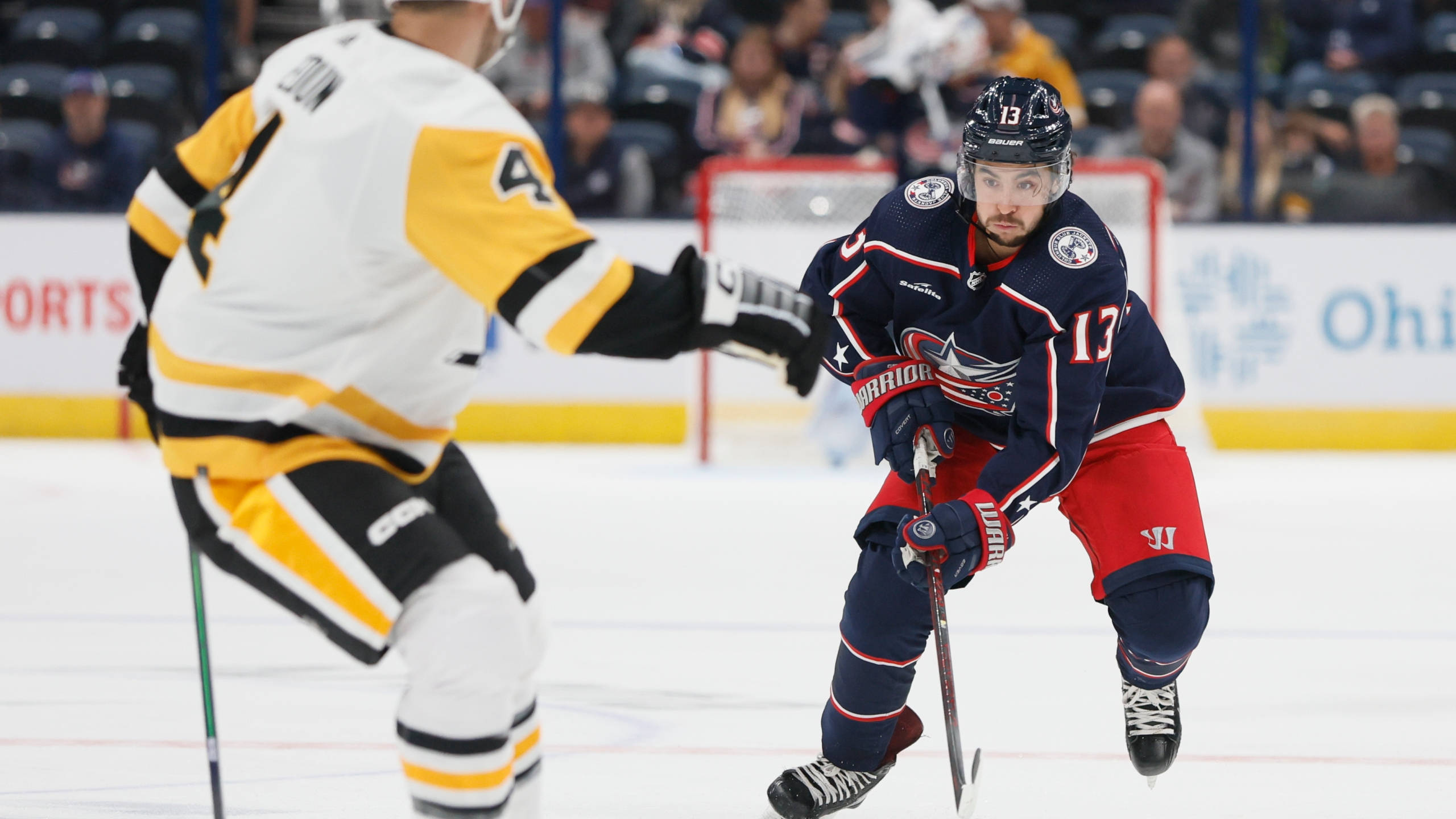 NHL冰球：約翰尼·高德魯對戰匹茲堡企鵝隊 壁紙 — 兩名曲棍球運動員在燈光明亮的冰場上，於職業比賽中激烈爭奪冰球。