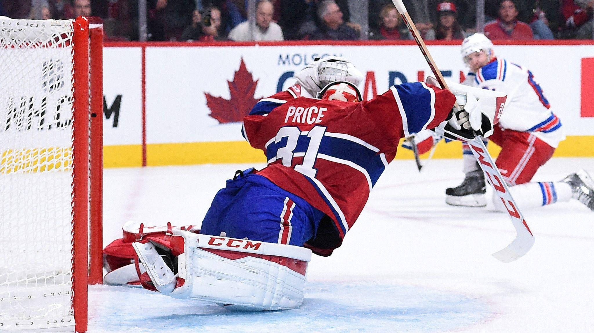 卡里·普萊斯 NHL 蒙特利爾加拿大人隊 防守球門攝影 壁紙 — 一名身穿紅、藍、白色裝備的冰球守門員在激烈的冰上比賽中飛身撲救阻擋射門。