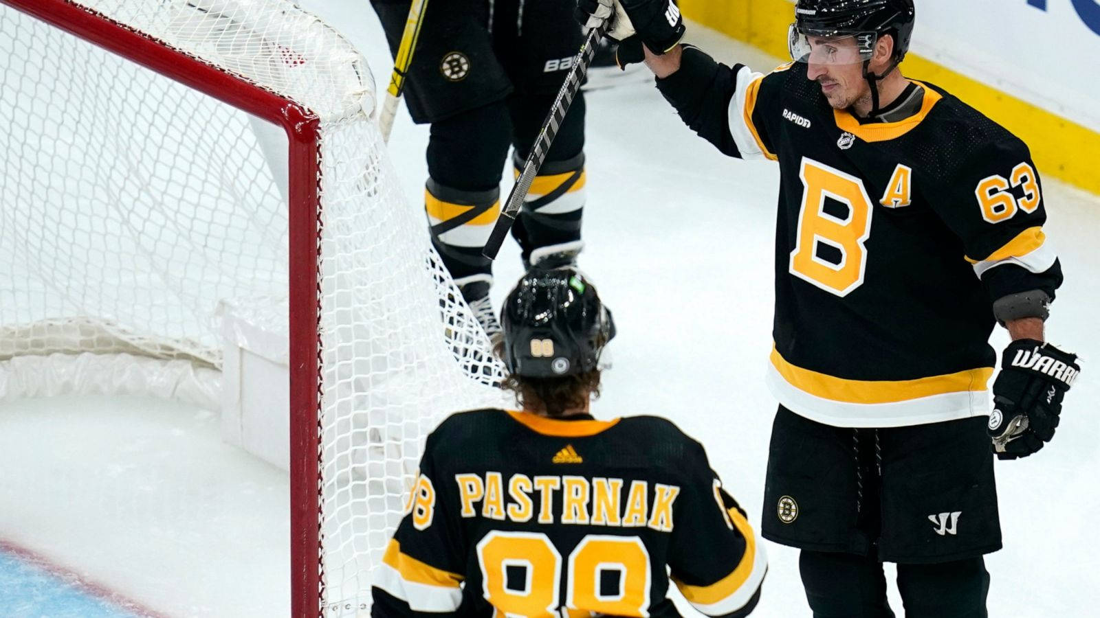NHL 冠軍：布萊德·馬奇安德與大衛·帕斯特納克慶祝 壁紙 — 兩名身穿黑色和金色球衣的曲棍球運動員在明亮的場館燈光下，在冰球場的球門附近慶祝。