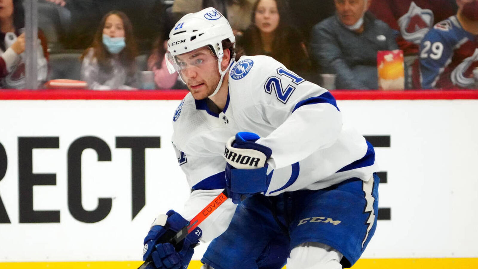 NHL 布雷登·波因特 21號球衣 壁紙 — 一名專注的曲棍球運動員身穿白色和藍色制服，在冰上激烈滑行，背景有觀眾。
