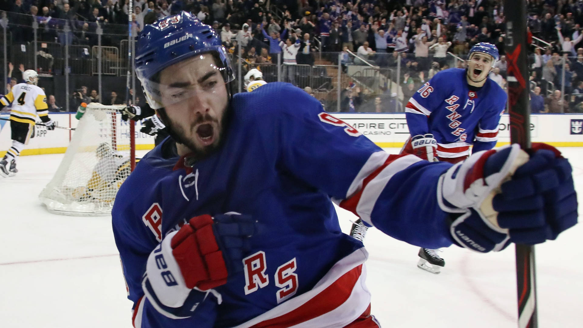 NHL 米卡·齊巴內賈德對陣匹茲堡企鵝隊慶祝制勝進球 壁紙 — 一位紐約遊騎兵冰球球員在入球後，在隊友於背景慶祝下，發出勝利的吶喊。