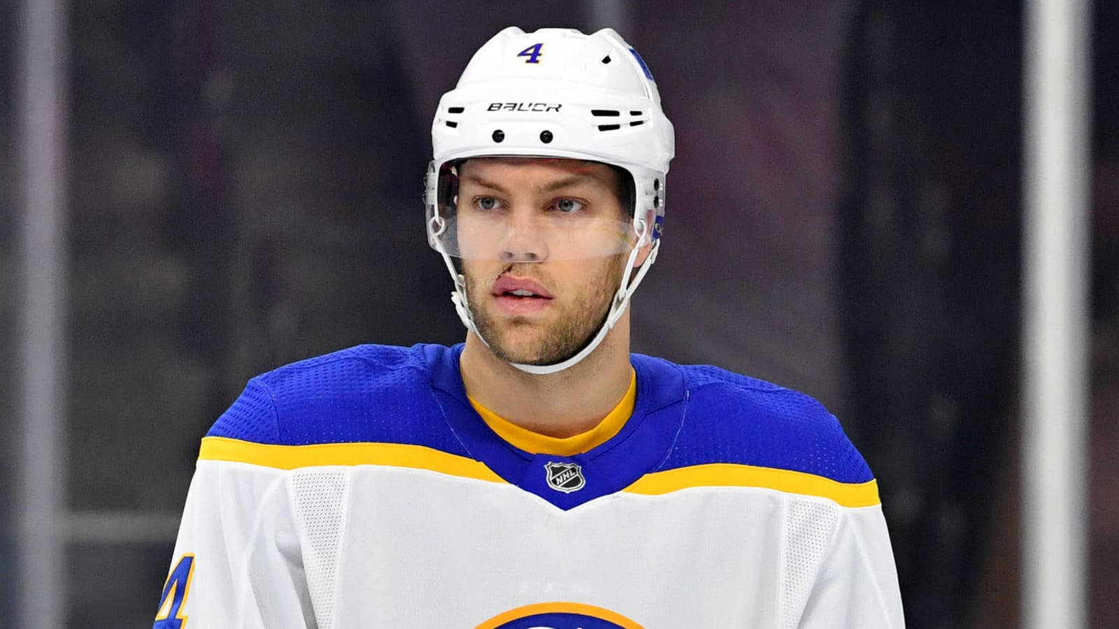 NHL埃德蒙頓油人隊04號泰勒·霍爾 壁紙 — 一名專注的曲棍球運動員身穿白色、藍色和黃色球衣，背號四號，在比賽中凝視前方。