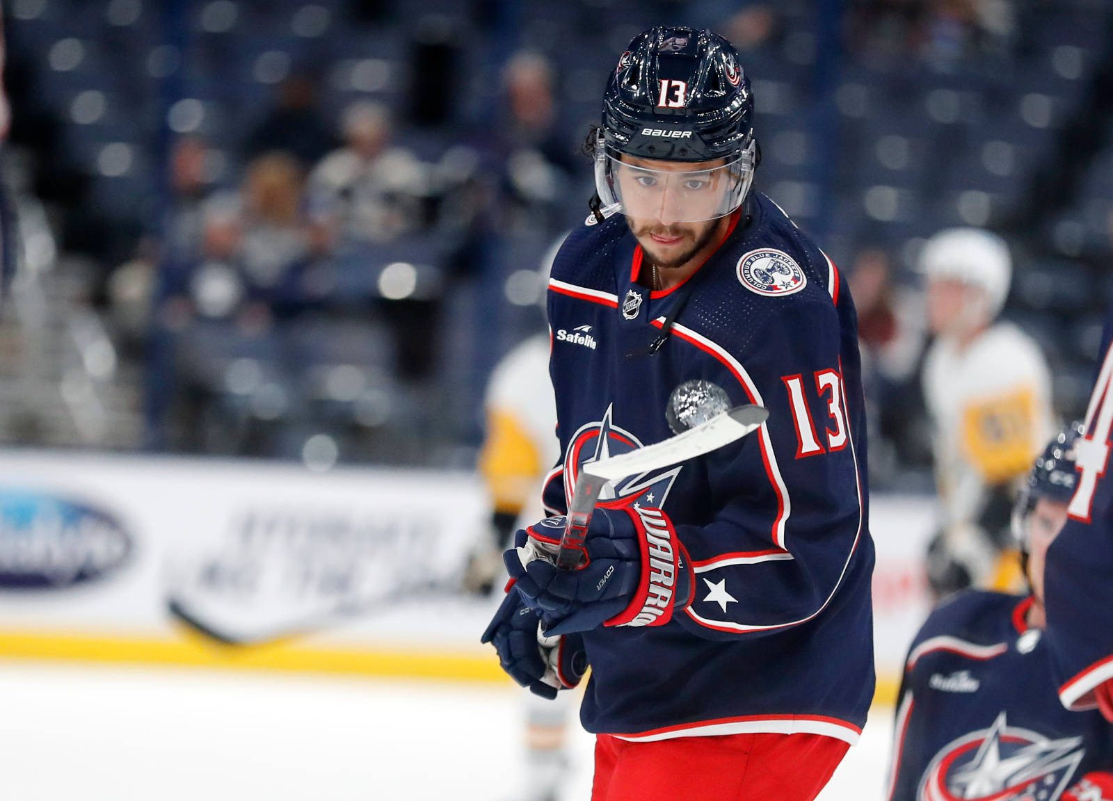 NHL冰球：克里夫蘭藍衣隊約翰尼·高德魯 壁紙 — 一位專注的曲棍球運動員身穿海軍藍球衣，號碼13，手持球棍在冰上滑行。