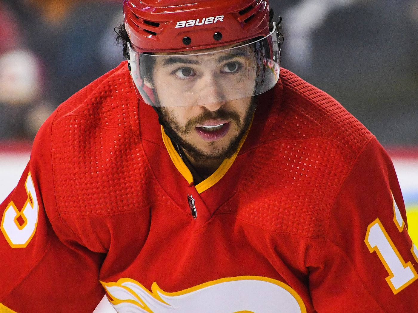 NHL冰球：卡爾加里火焰隊約翰尼·高德魯賽事實拍 壁紙 — 冰上比賽期間，一名身穿紅色球衣和頭盔、專注的冰球運動員的特寫。