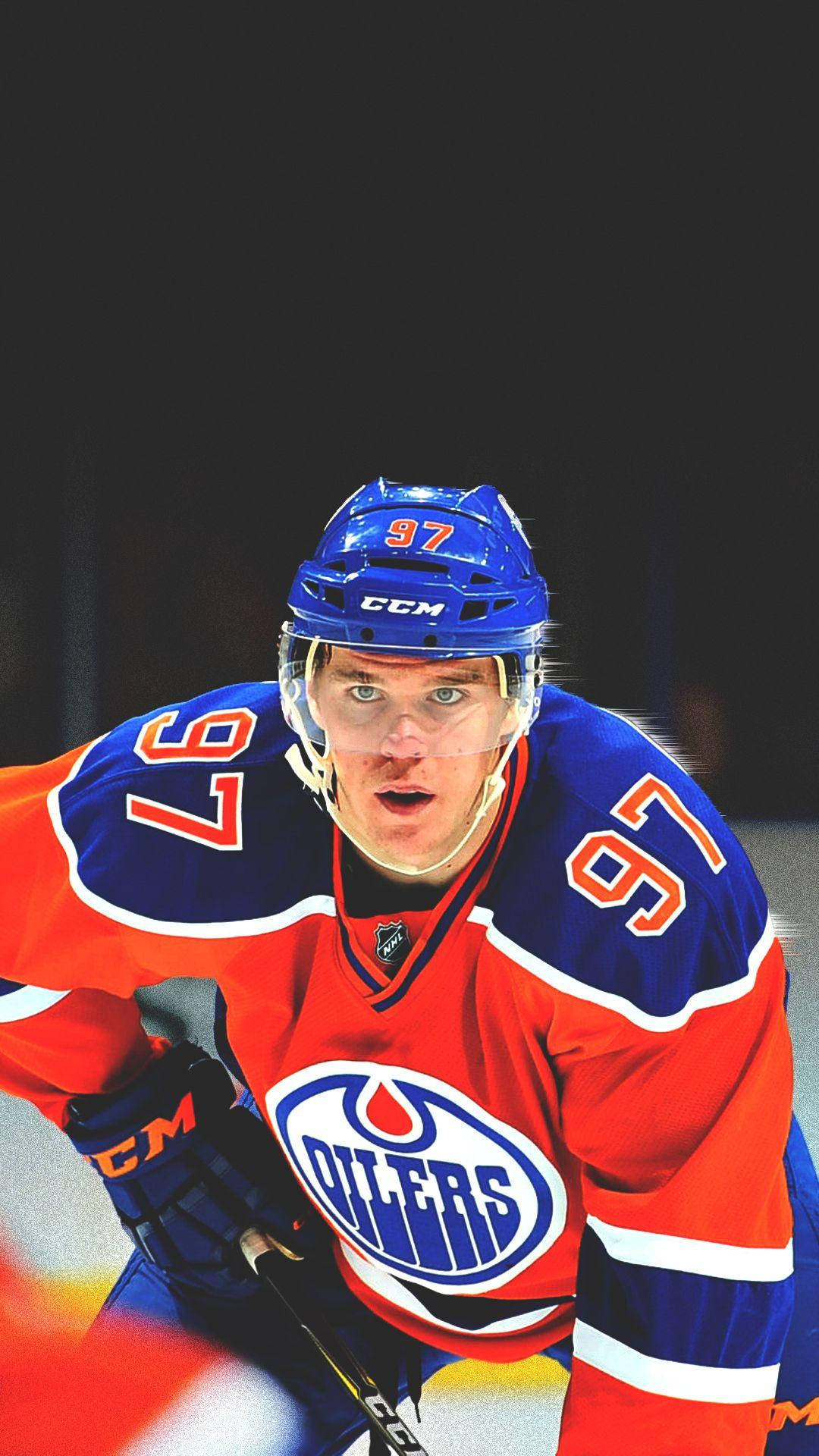 NHL球員康納·麥克戴維嚴肅表情 壁紙 — 一名專注的冰球運動員身穿紅藍色的愛民頓油人隊97號球衣，在比賽中凝視著。