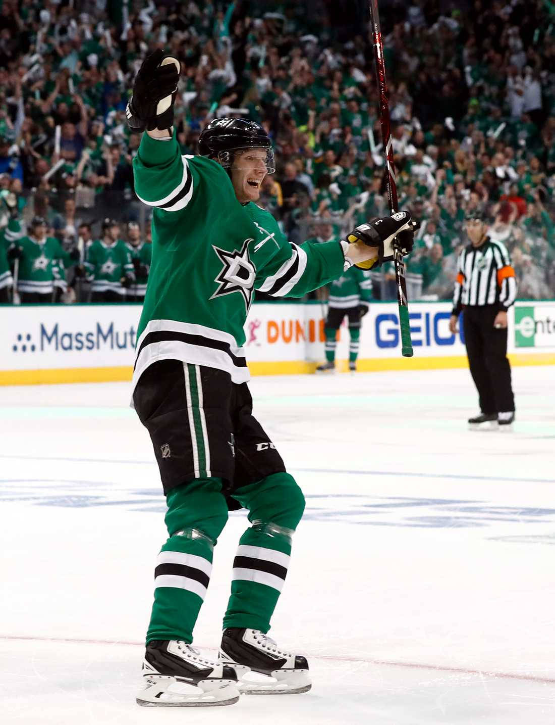 NHL球星約翰·克林格伯格賽後慶祝瞬間 壁紙 — 一位身穿綠色球衣的達拉斯星隊冰球球員在冰上舉拳慶祝入球，身後觀眾歡呼。