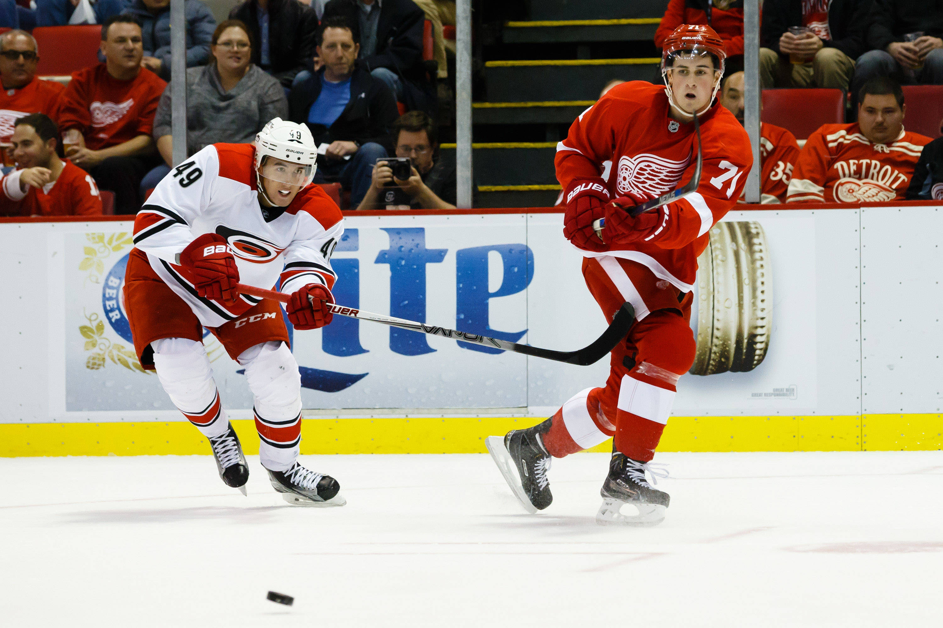 NHL第71號球員迪倫·拉金 壁紙 — 兩名身穿紅白球衣的曲棍球運動員在冰場上爭奪冰球，背景有觀眾。