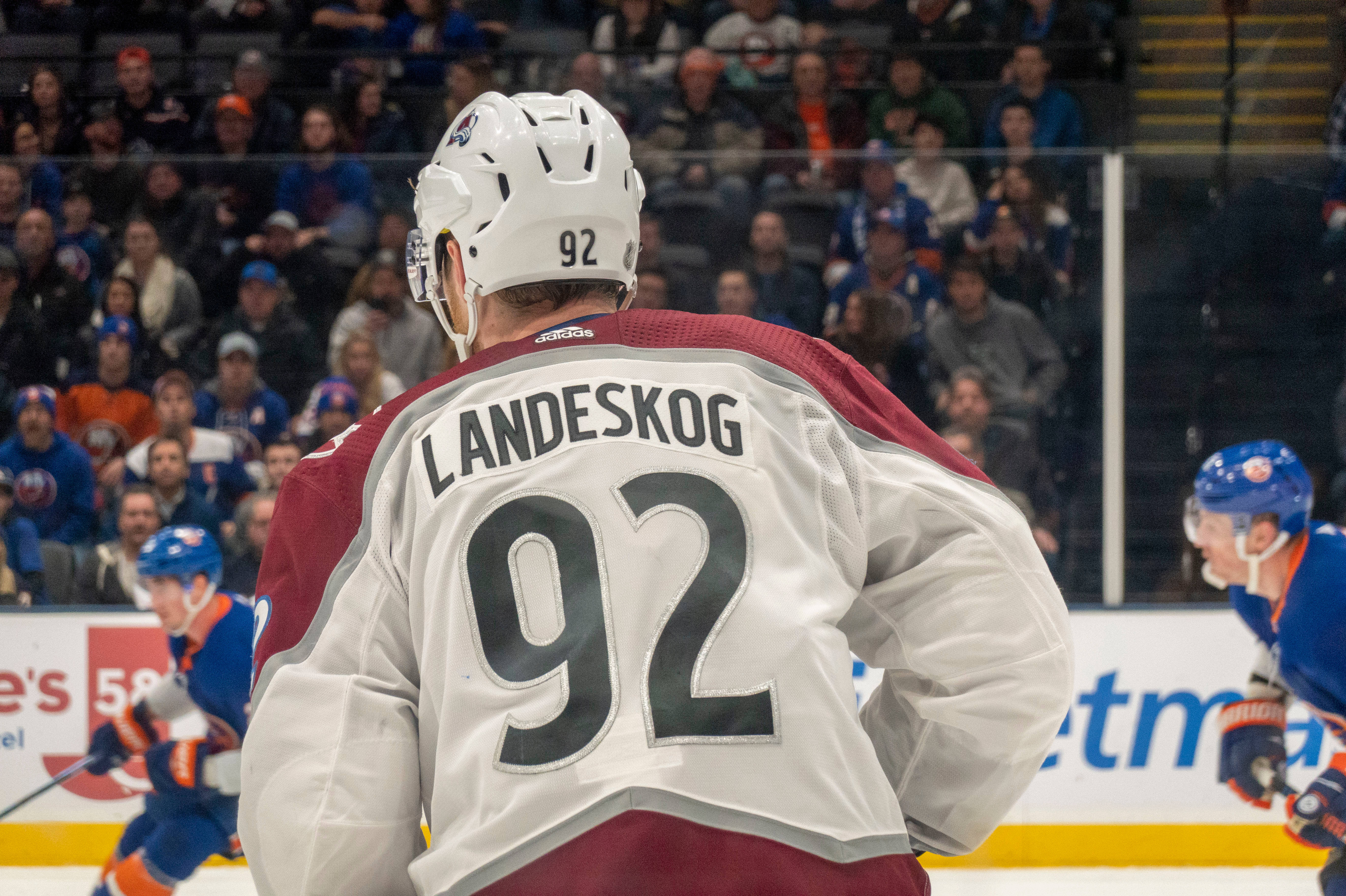 NHL隊長加布里埃尔·蘭德斯科格 壁紙 — 一名身穿92號球衣、背面印有Landeskog名字的冰球運動員在比賽中站在冰上，面向人群。