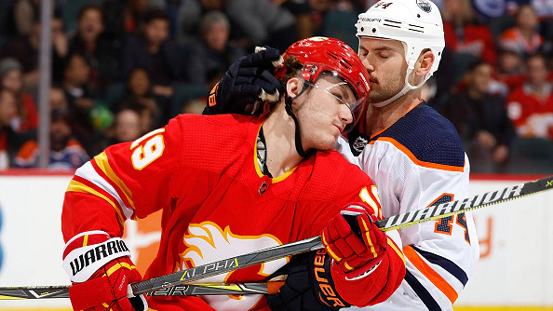 NHL馬修·特卡丘克與扎克·卡西安對決 壁紙 — 兩名身穿紅白球衣的曲棍球運動員在激烈的比賽中相撞，背景有觀眾。