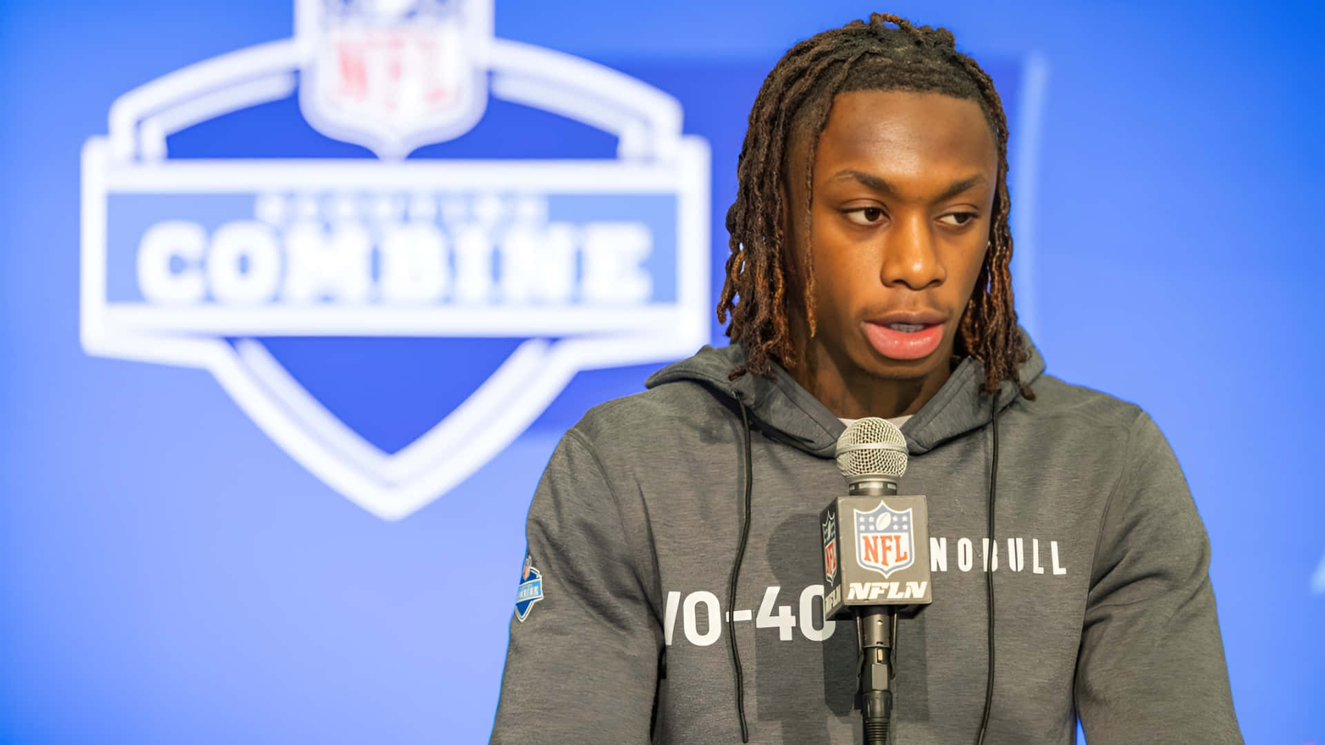  壁紙 — 年輕的足球運動員梳著辮子，在NFL聯合試訓記者會上對著麥克風發言。