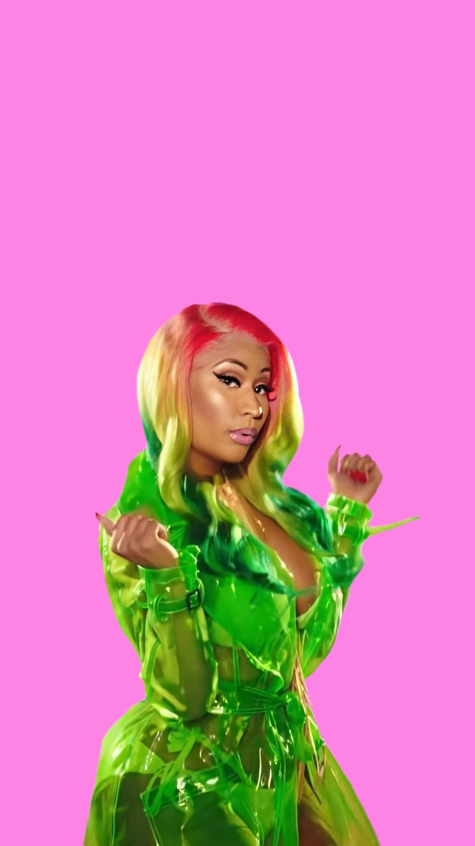 Nicki Minaj 穿綠色 壁紙 — 一位擁有彩虹色頭髮的女性，穿著閃亮的綠色服裝，背景為純粉色。