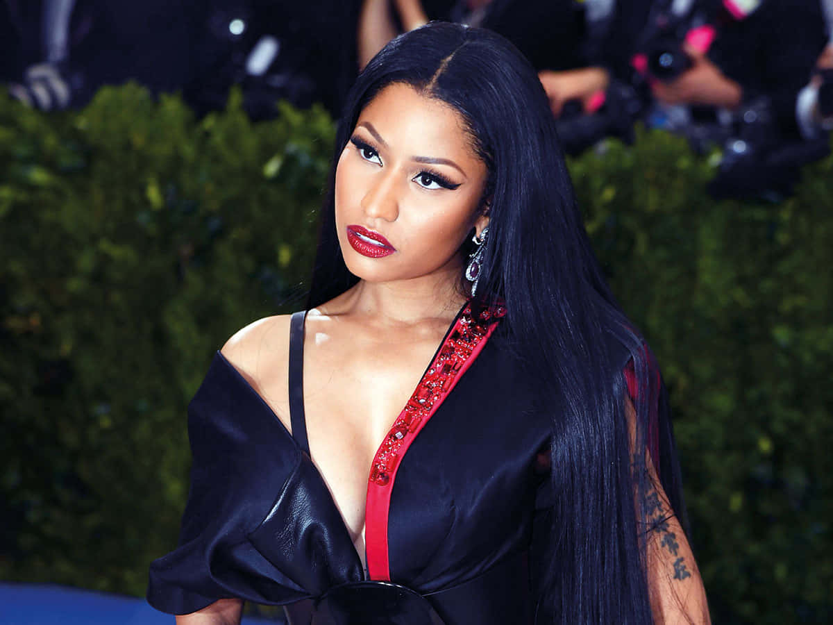 Nicki Minaj 在紅地毯活動中穿著帶有紅色點綴的黑色緞面連衣裙。