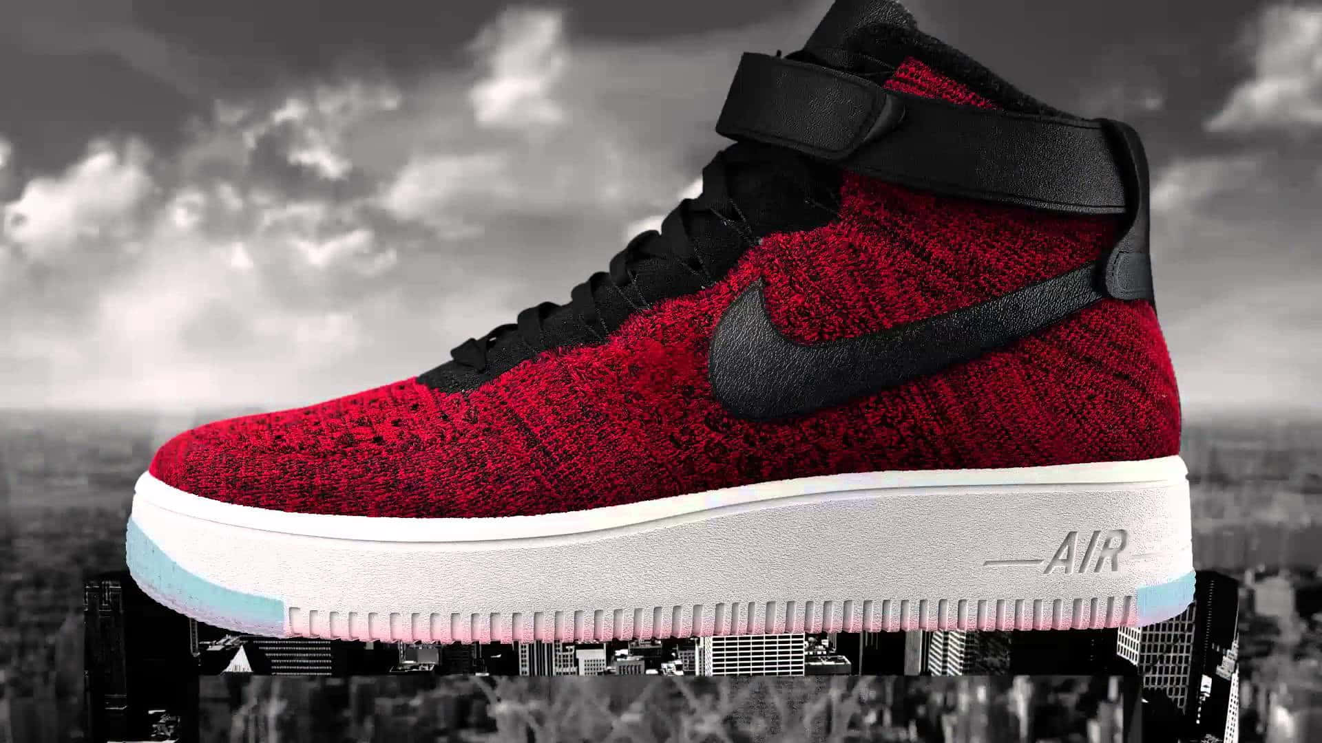 以Nike AF1鞋款釋放你的個人風格 壁紙 — 一雙鮮紅色高筒運動鞋帶有黑色勾勾，漂浮在陰天下的單色城市景觀之上。