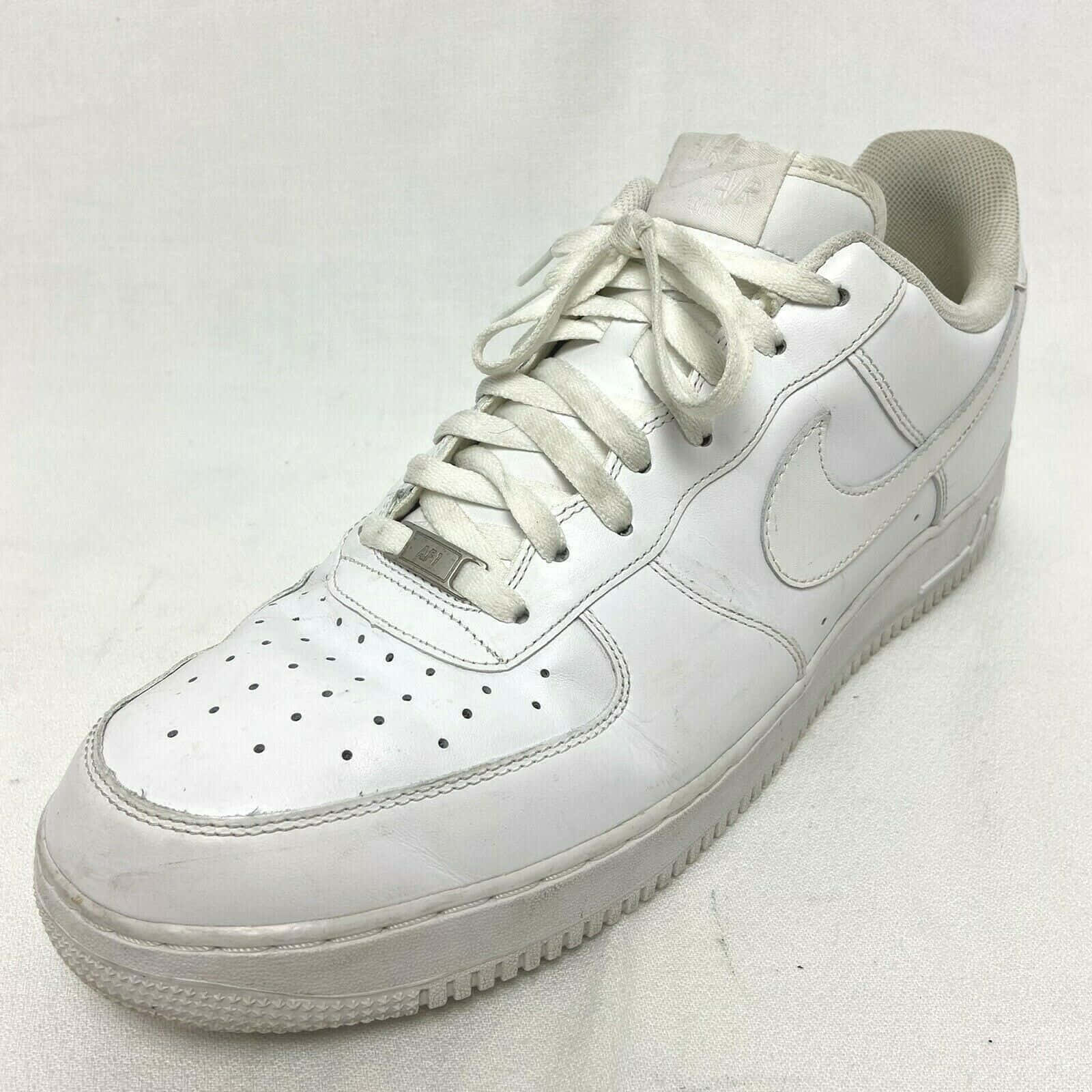 二手白色Nike Air Force 1圖像 壁紙 — 一雙磨損的白色Nike Air Force 1運動鞋，皮革有刮痕，鞋帶骯髒，放在純白色背景上。
