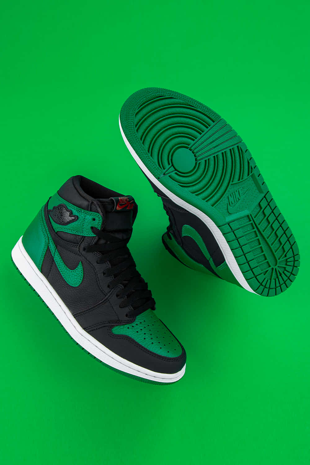 經典Nike Air Jordan鞋款 壁紙 — 一對黑色和綠色的高筒運動鞋，白色鞋底，展示在充滿活力的綠色背景上。