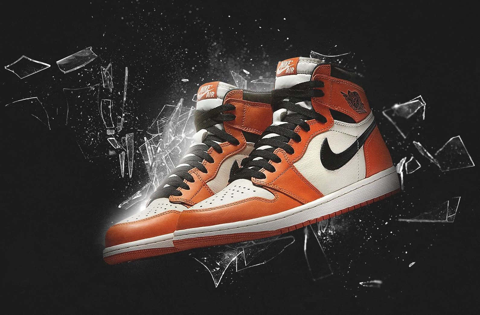 穿上 Nike Air Jordan 鞋款，躍得更高 壁紙 — 一對橙色和白色的 Air Jordan 1 運動鞋在黑色背景上衝破碎玻璃。