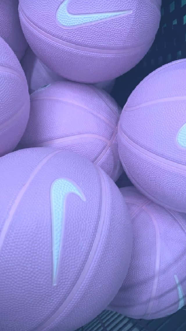 以Nike籃球釋放內在冠軍 壁紙 — 薰衣草色籃球帶有發光白色Nike標誌，堆疊在籃子中的特寫。