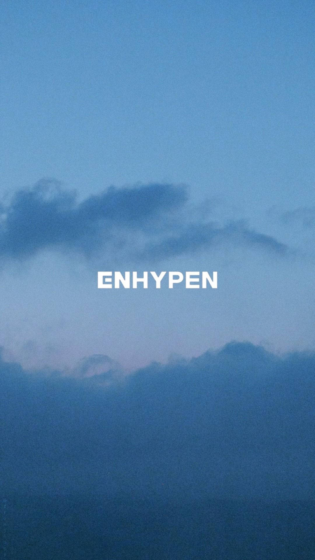 文字ENHYPEN在帶有柔和雲朵的藍色暮色天空上。