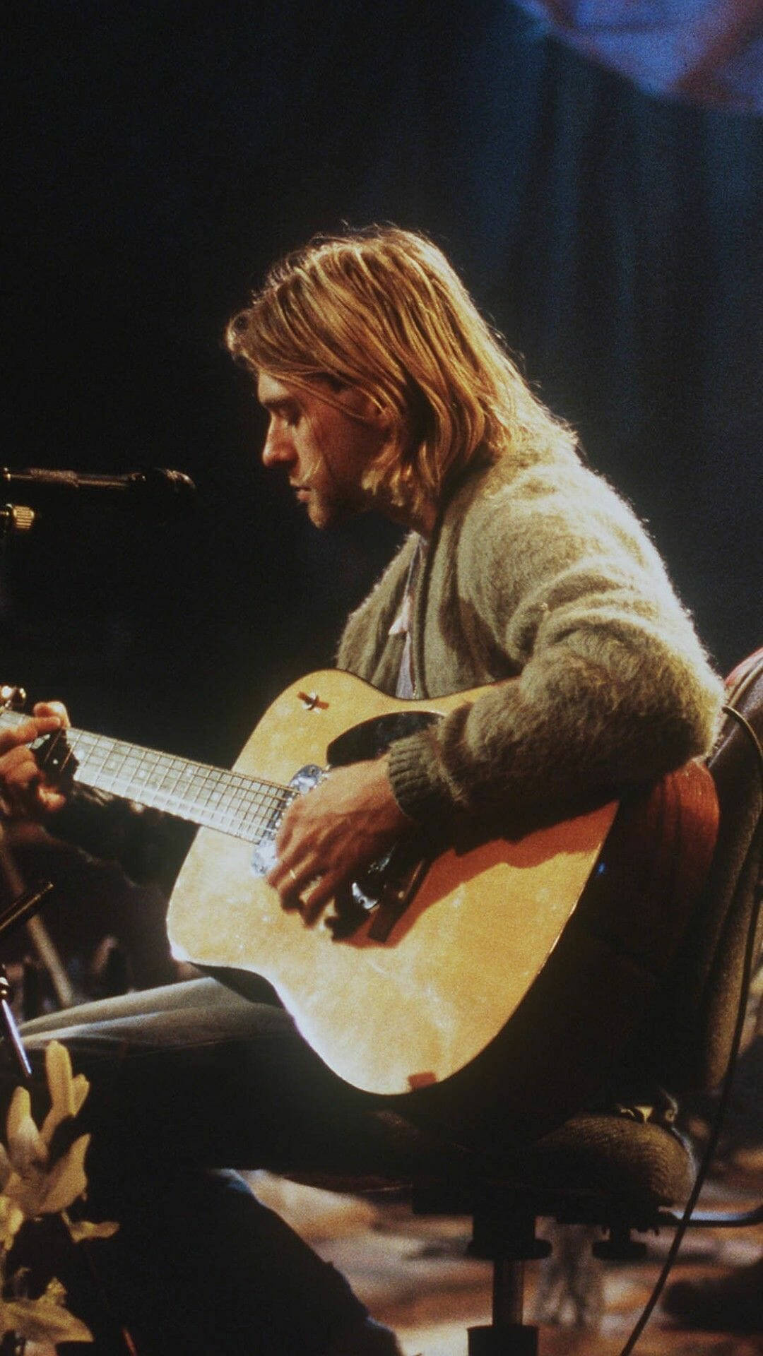 Kurt Cobain 在聚光燈下於舞台上彈奏木結他。