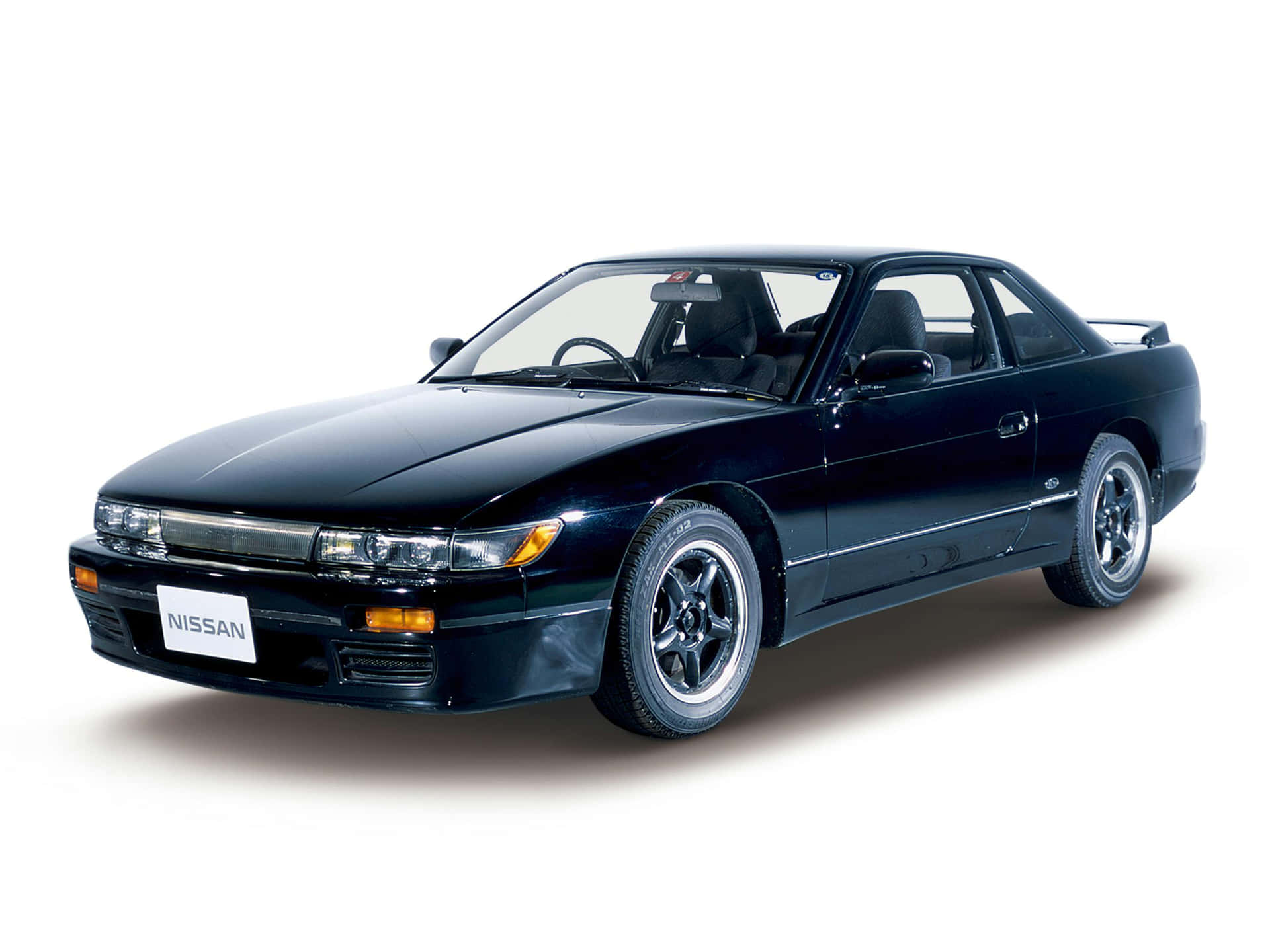 Nissan 240sx經典跑車 壁紙 — 一輛時尚的黑色日產運動轎跑車，配備銀色輪圈和光澤飾面，在攝影棚燈光下展示。