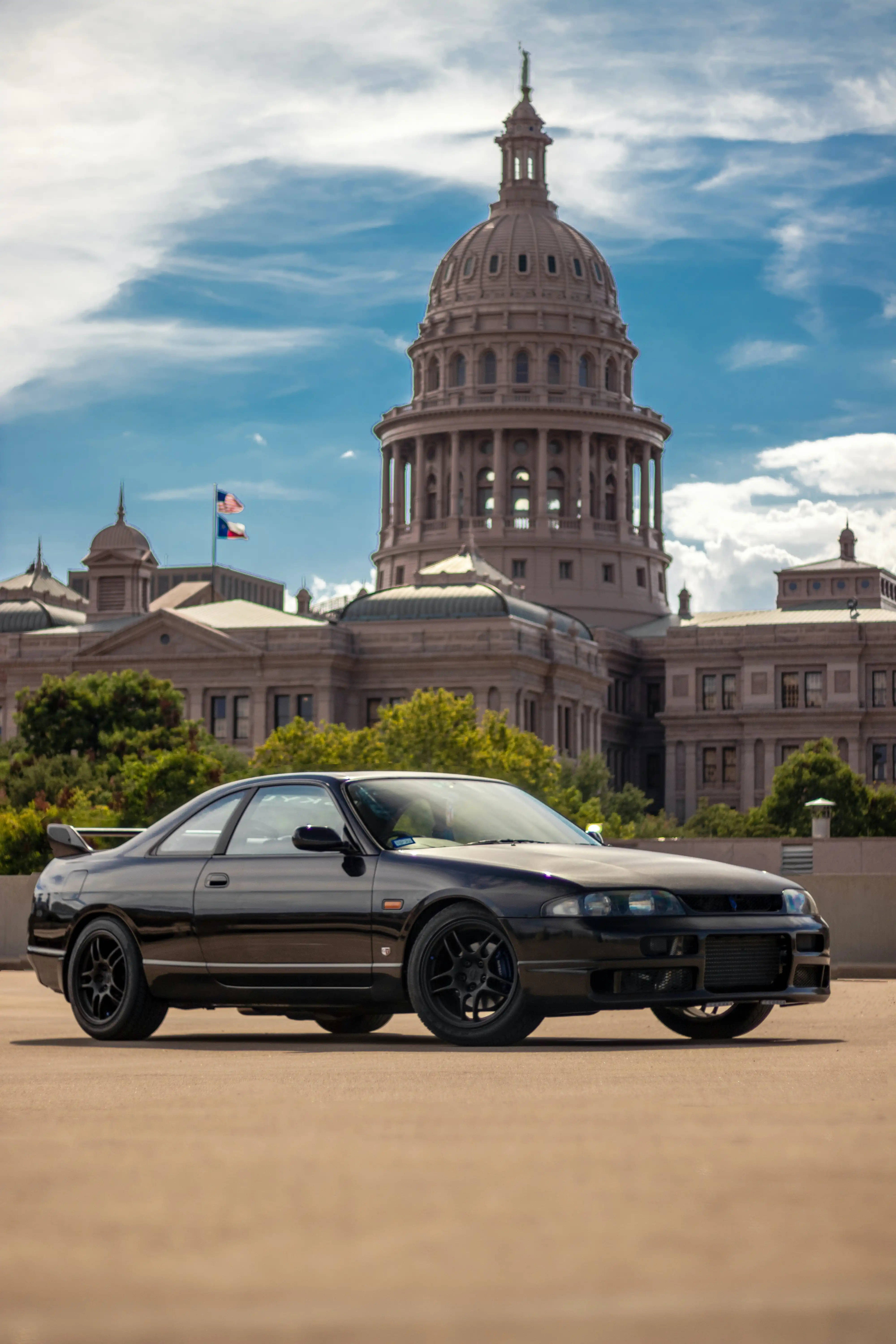 Nissan GT-R 車款於科羅拉多州 壁紙 — 一架時尚的黑色跑車停泊在宏偉的圓頂州議會大廈前，天空湛藍，白雲點綴。