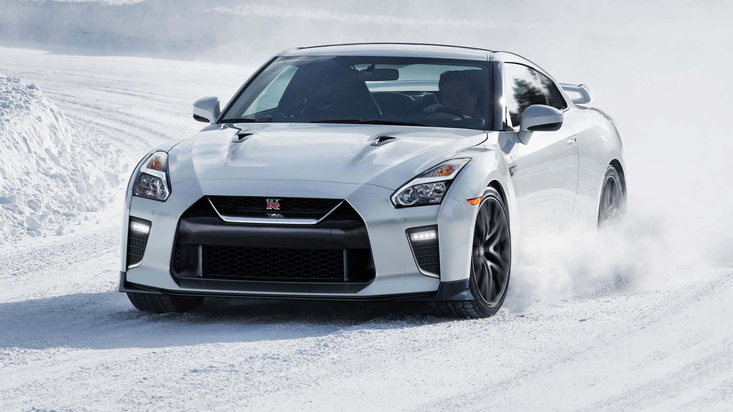 白色Nissan R35 GT-R汽車雪地公路 壁紙 — 一輛白色日產GT-R在深雪中強力飄移，在冬季道路上揚起戲劇性的粉雪雲。