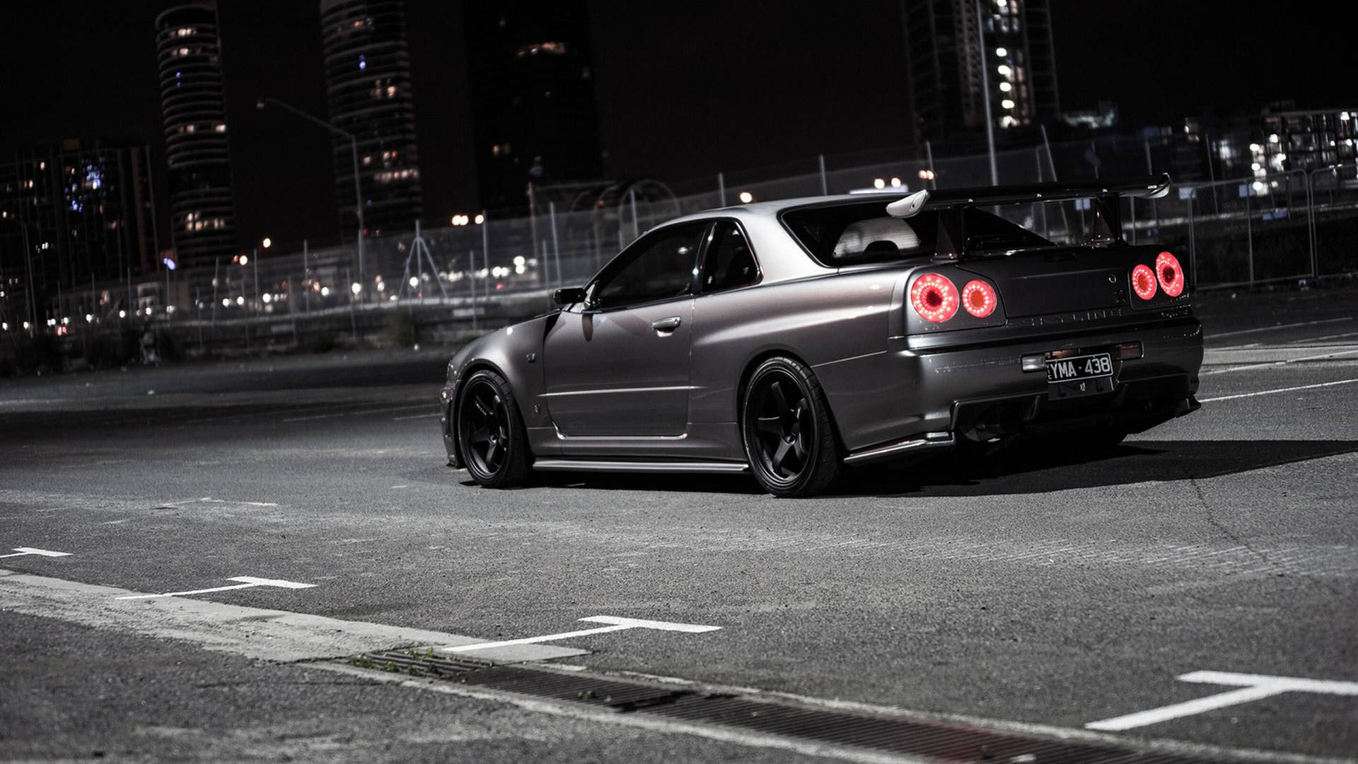 啞光灰色日產Skyline GT-R，紅色尾燈，停在夜晚城市街道。