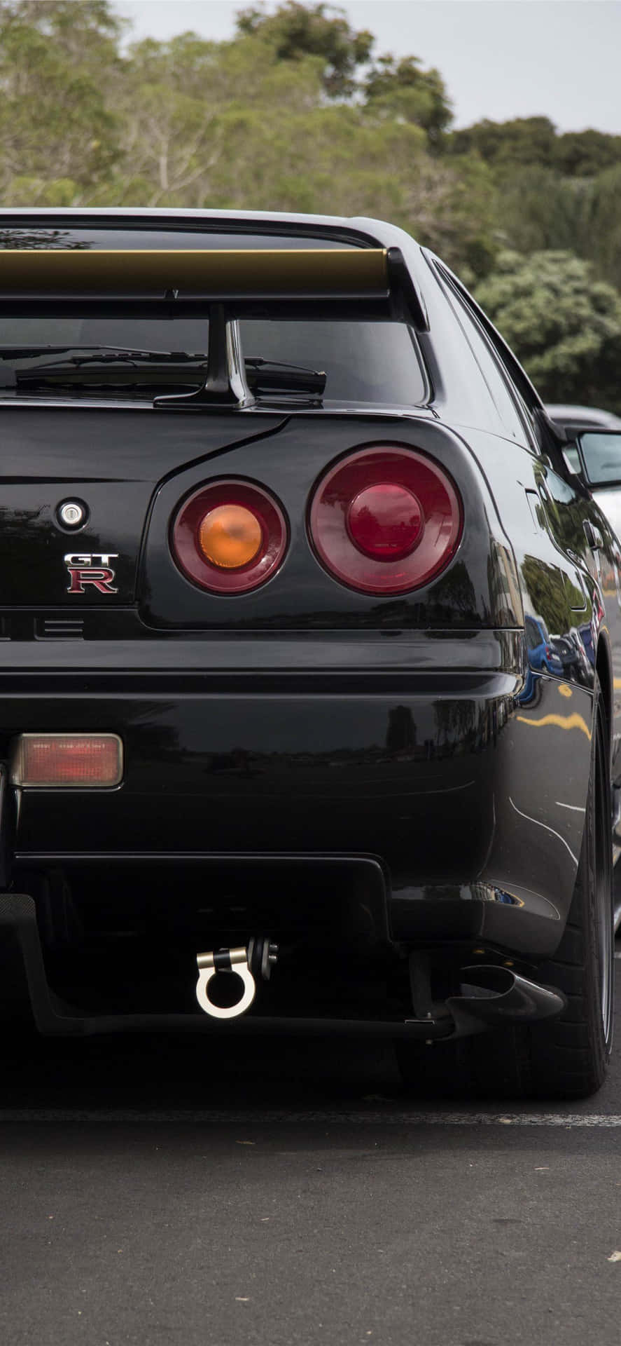 黑色日產GT-R跑車停泊，後面有樹木。