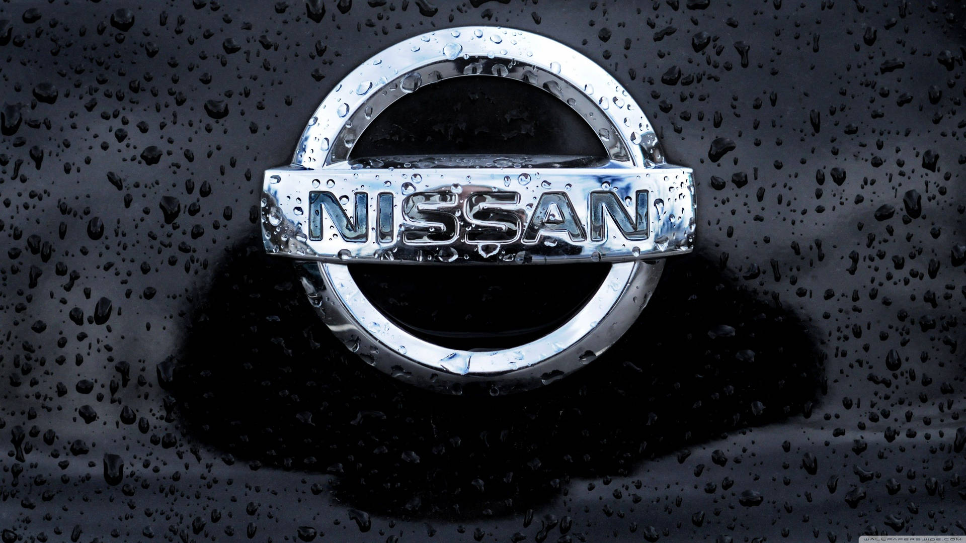 日產汽車標誌被雨滴覆蓋在深色表面上。