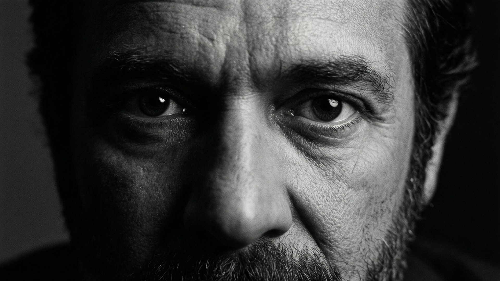 Close-up of a man's intense eyes and weathered face in black and white. 壁紙