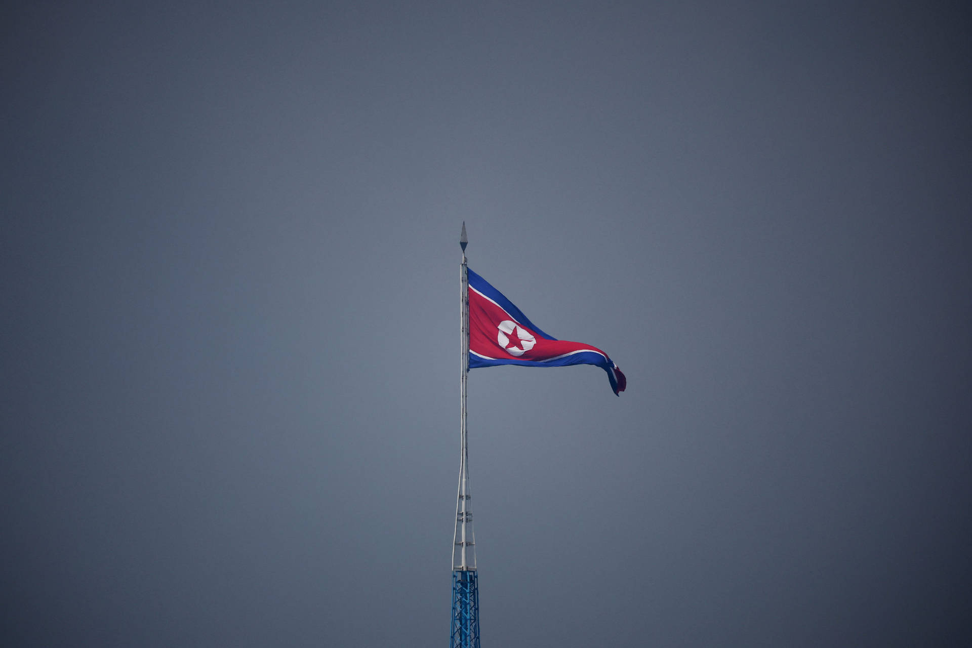 北韓國旗在陰天天空下的旗桿上飄揚。