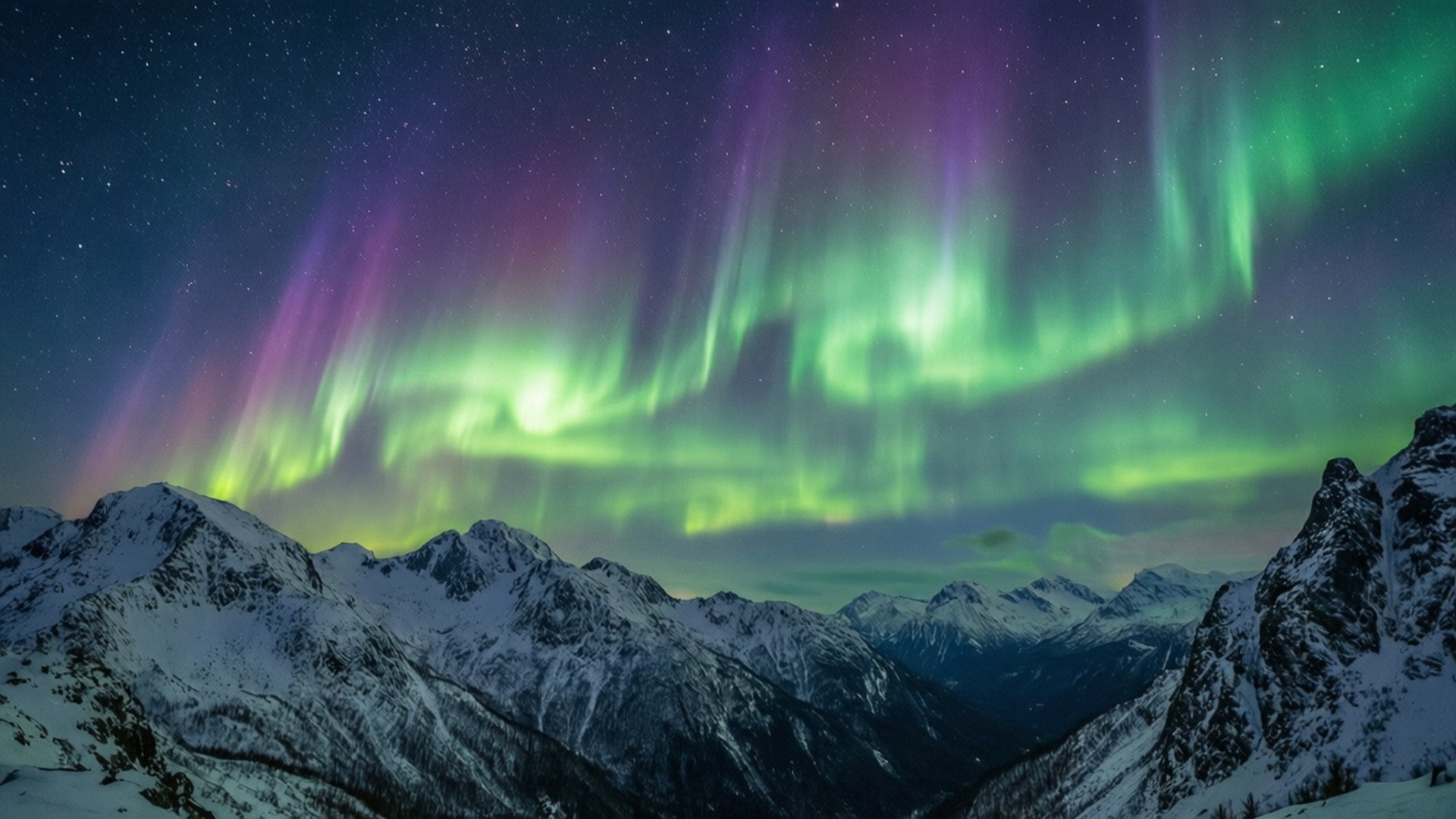 Aurora borealis glowing over snowy mountains under a starry sky. 壁紙