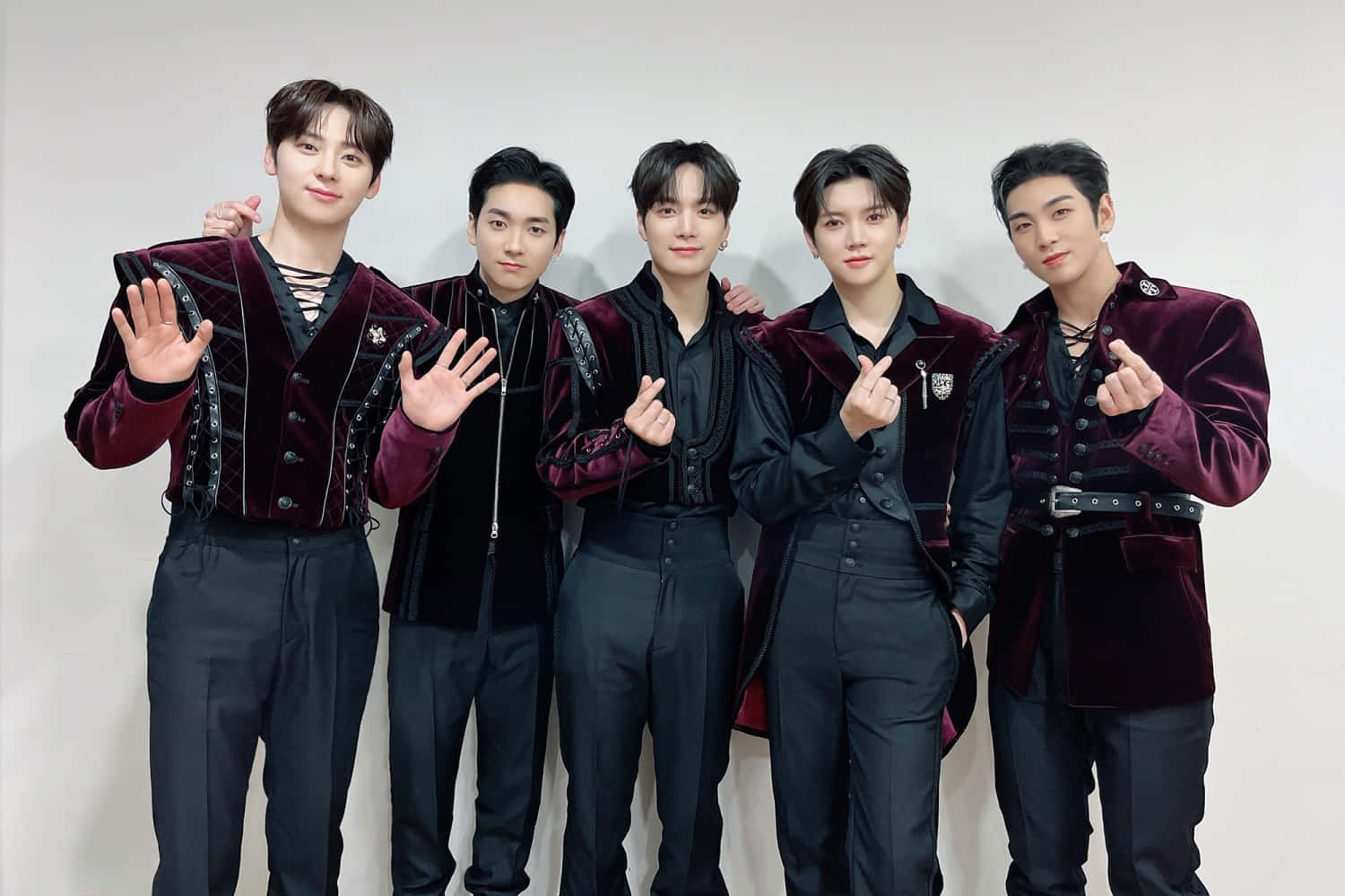 Nuest K-pop 男子團體演出前照 壁紙 — 五位時尚年輕男士穿著相配的酒紅色天鵝絨外套，在純白色背景前自信地擺姿勢。