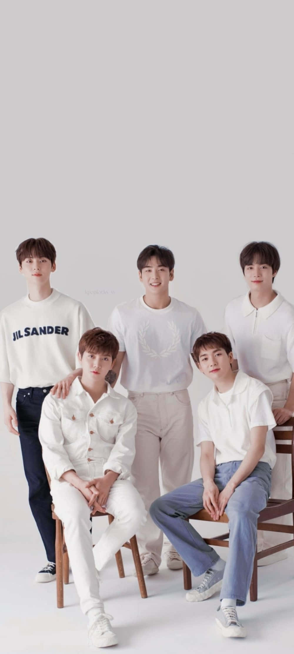 Nuest K-pop 男子團體美學寫真 壁紙 — 五名身穿白色及淺色服裝的年輕男子，在白色攝影棚背景前，隨意地坐在木椅上擺姿勢。
