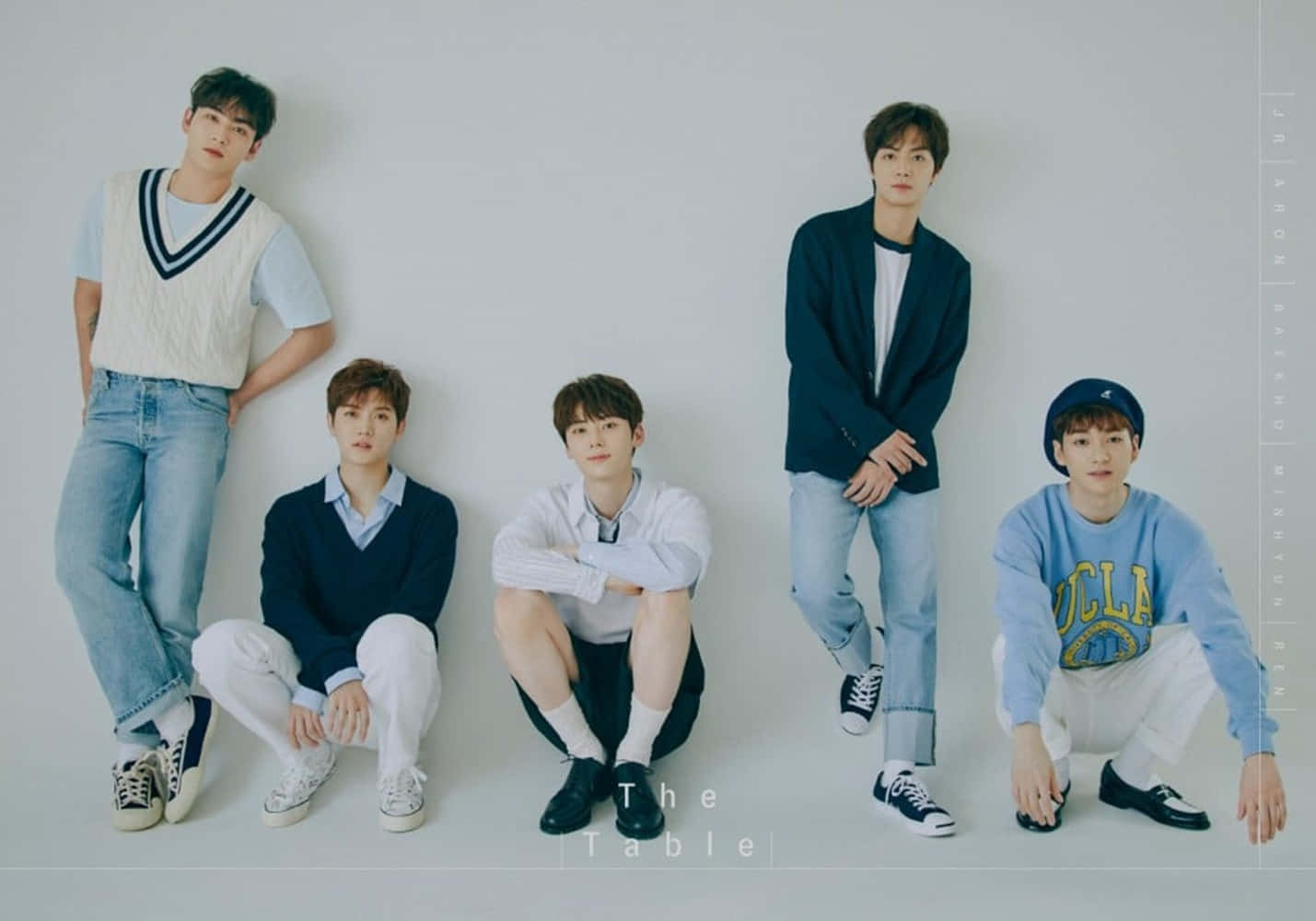 NUEST K-pop男子團體學院風造型 壁紙 — 五位年輕男子穿著休閒服裝，在樸素的白色牆壁前以放鬆的姿勢和柔和的工作室燈光擺姿勢。