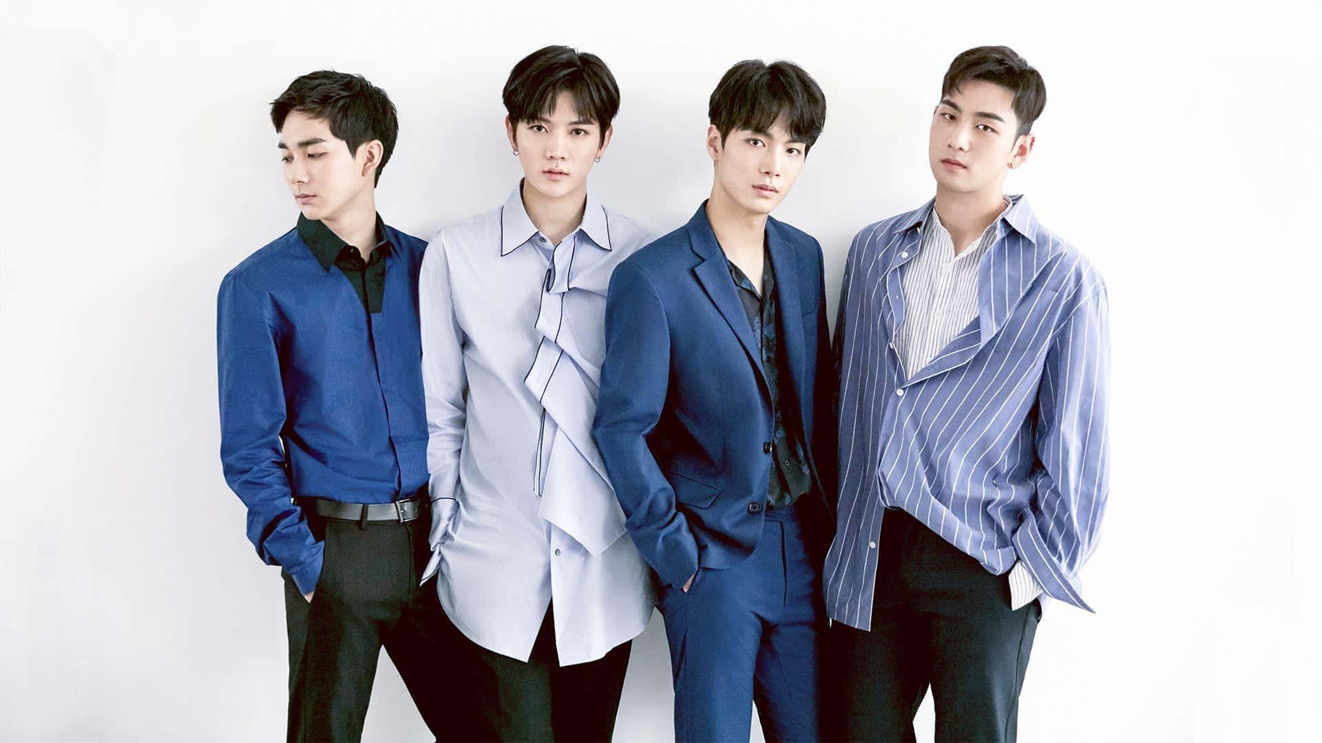 NUEST K-pop男子團體藍色造型 壁紙 — 四位身穿藍色和灰色服裝的時尚年輕男性在純白色背景前自信地擺姿勢。