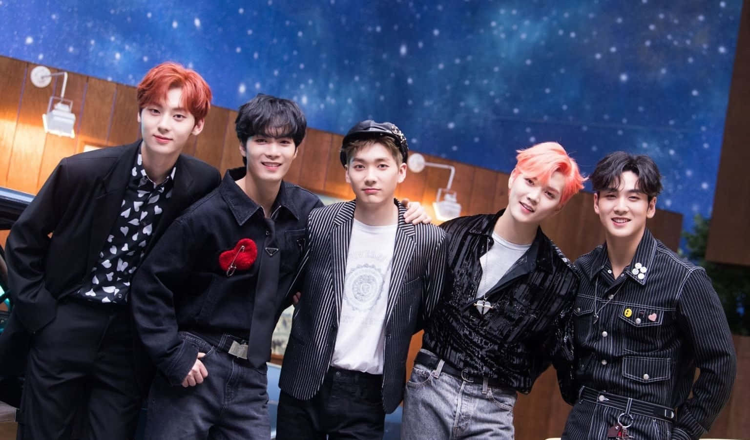 NUEST K-pop男子團體酷感拍攝 壁紙 — 五位時尚的年輕男性，擁有色彩繽紛的頭髮，在工作室的星空藍色背景下自信地擺姿勢。