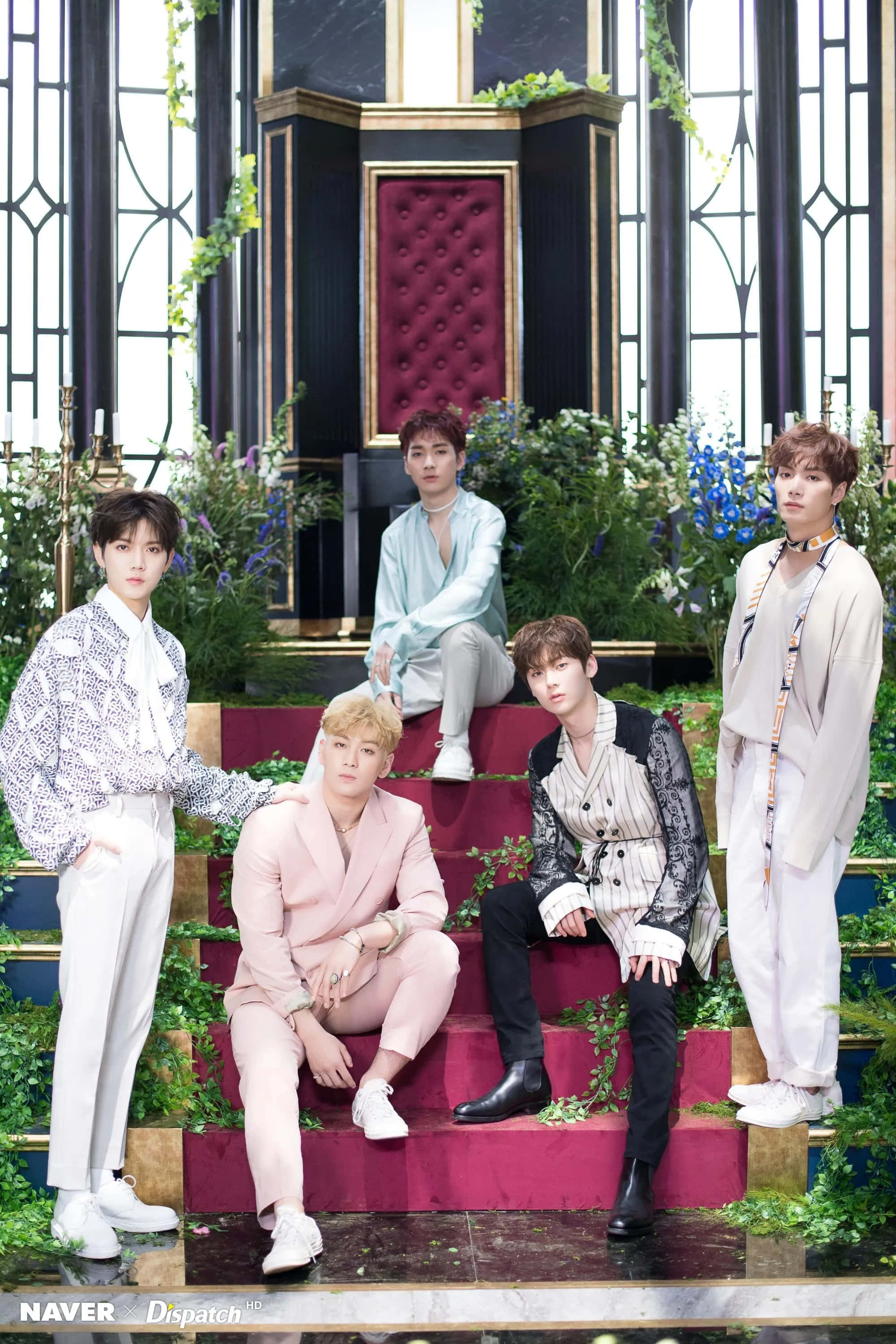NUEST KPOP 男子團體古典風拍攝 壁紙 — 五位時尚年輕男士在華麗的紅色階梯上擺姿勢，周圍環繞著茂密的綠植和彩色玻璃窗。