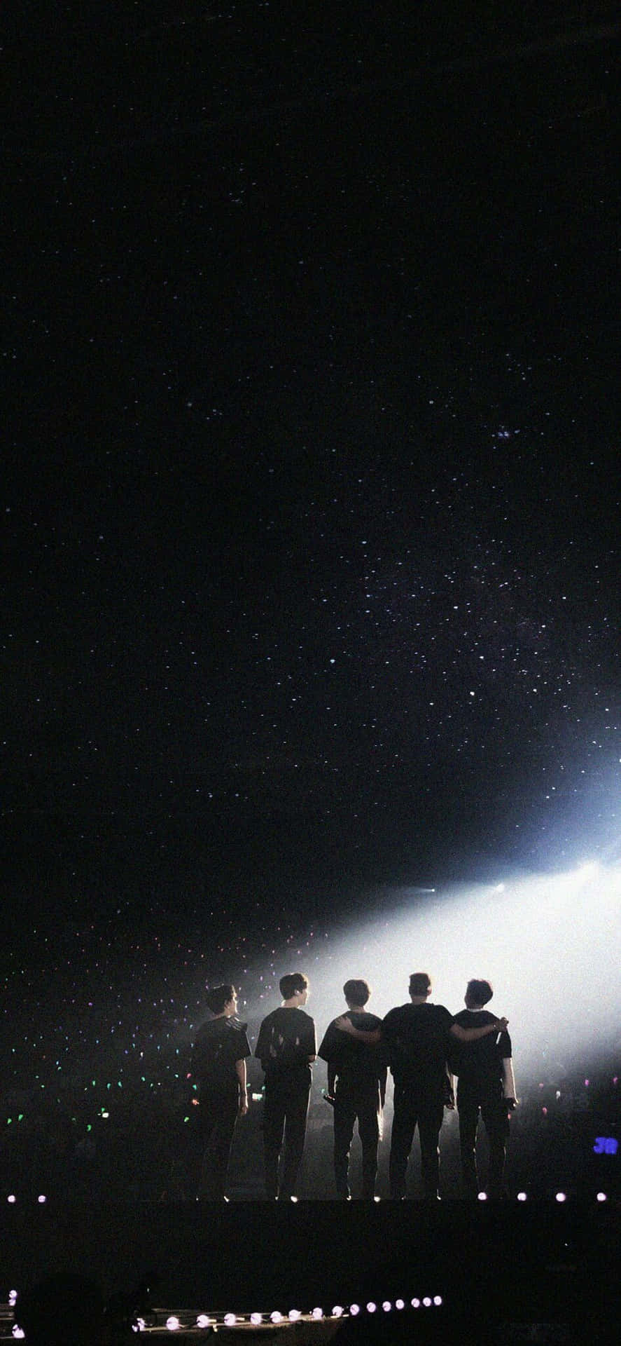 NUEST KPOP 男子團體音樂會美學照 壁紙 — 五個剪影人物站在舞台上，背景是星光燦爛的夜空，被明亮的聚光燈照亮。
