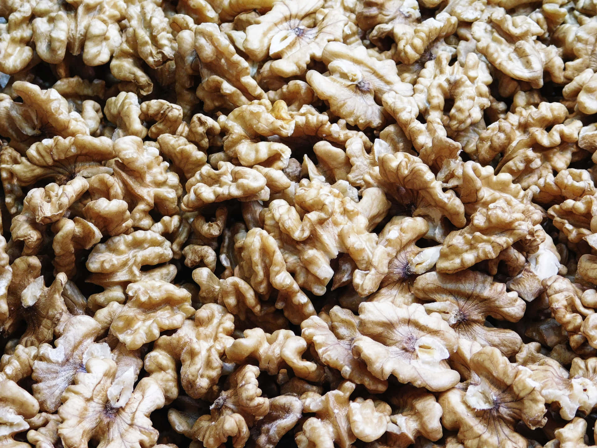 一堆帶殼核桃，顯示出詳細的脊狀紋理和自然的米色色調。