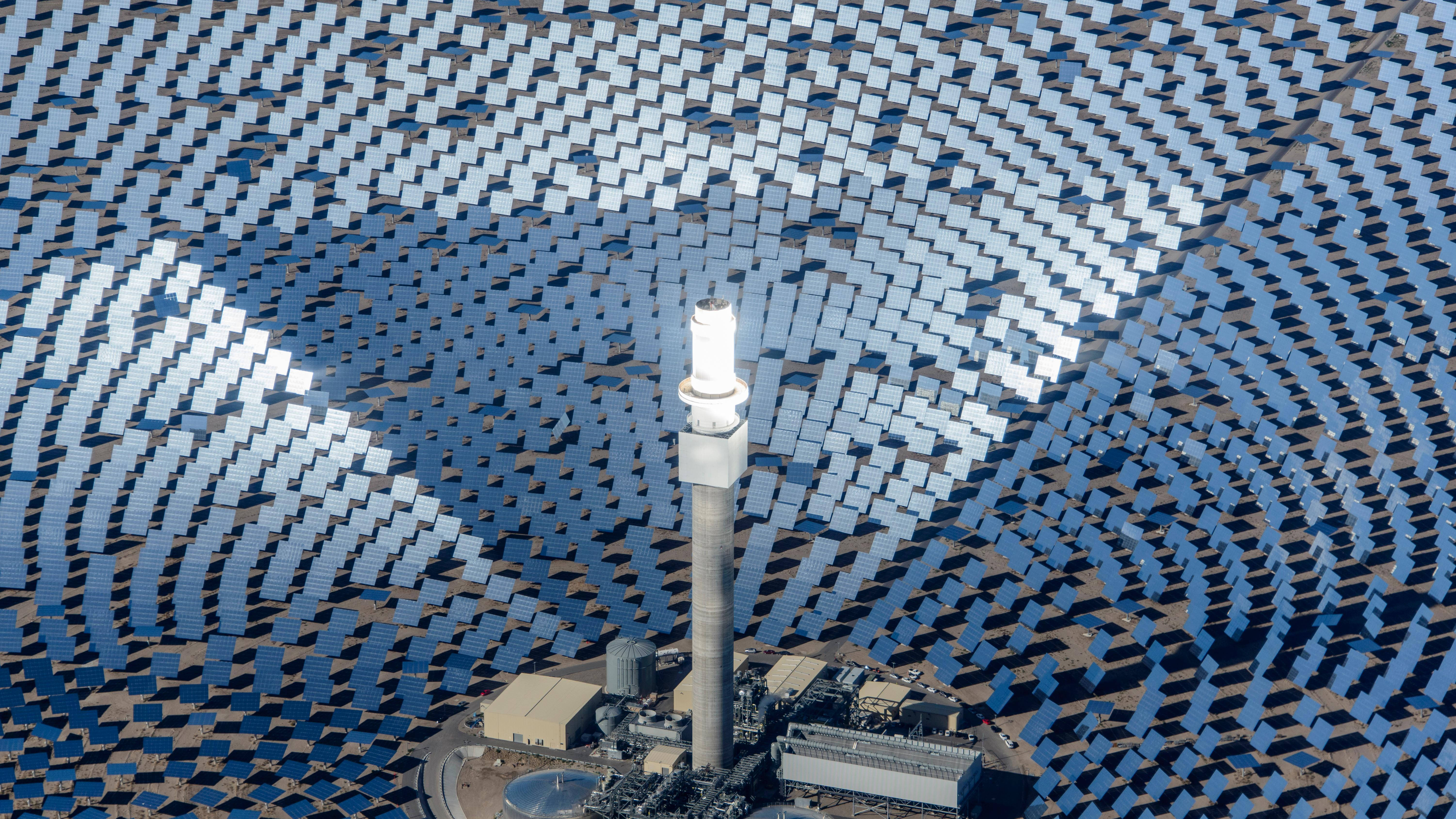 NV Energy電力站——提供清潔可持續能源 壁紙 — 從空中俯瞰一座太陽能發電廠，數千塊藍色反光板圍繞中央塔樓排列成同心圓。